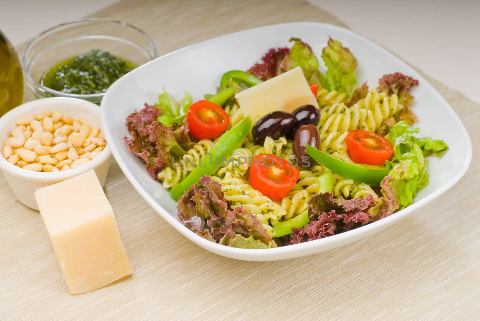 fresh healthy homemade italian fusilli pasta salad with parmesan cheese,pachino cherry tomatoes, black olives and mix vegetables ,dressed with extra-virgin olive oil and pesto sauce