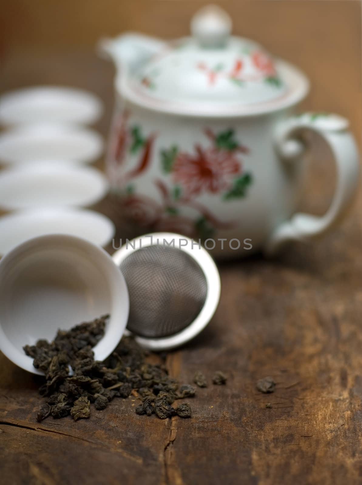 dry green chinese tea set,with strainer closeup,cups and teapot on background over old wood board