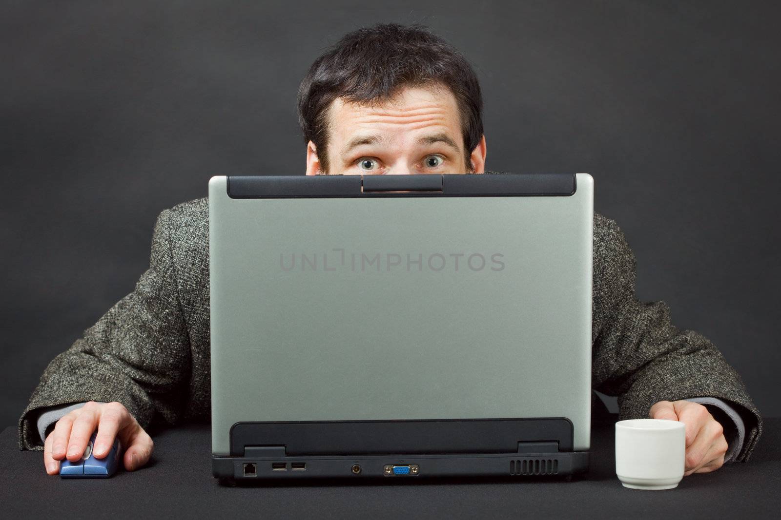 Frightened people hiding behind a computer screen on black