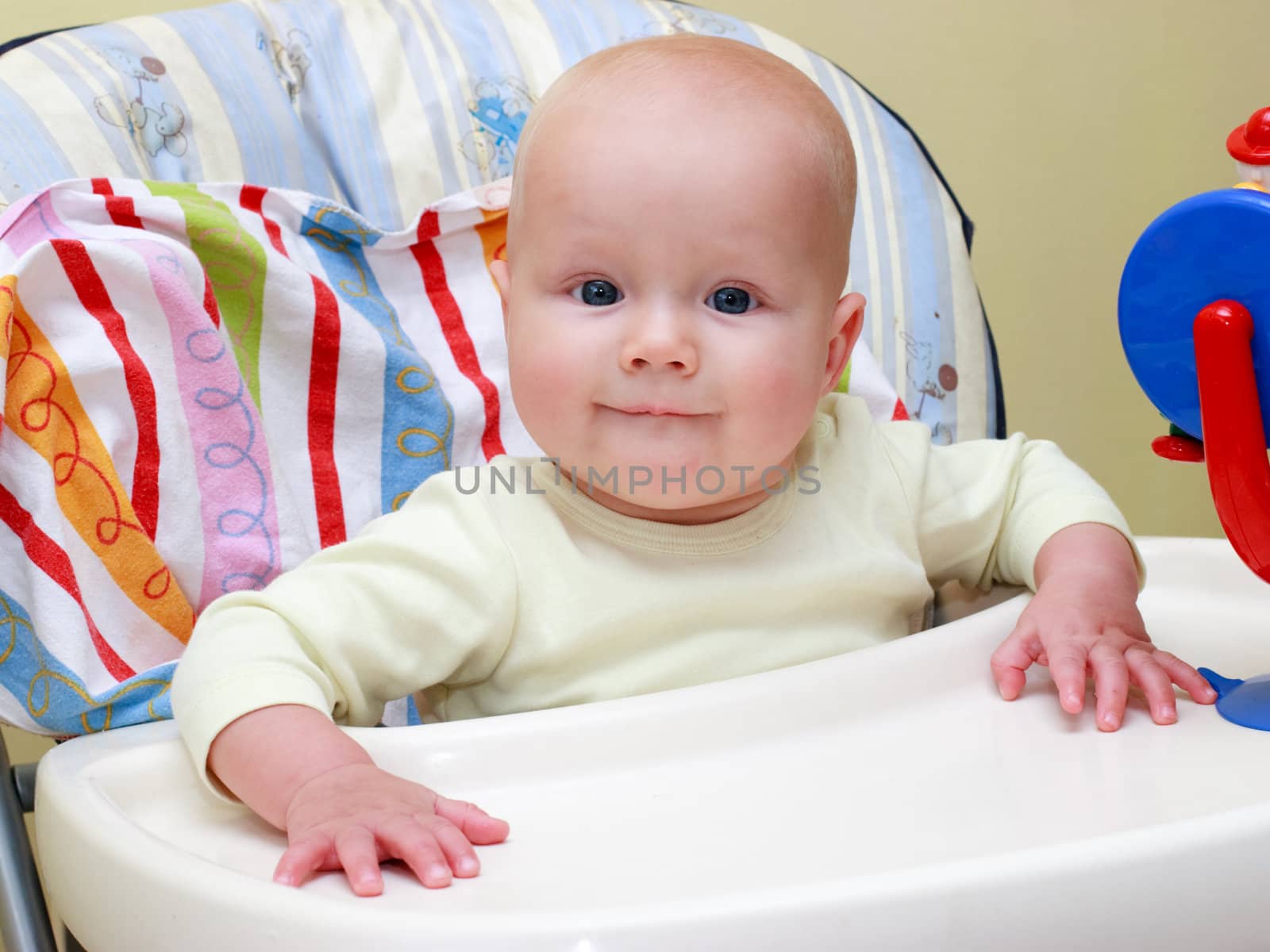 Seven month baby girl sitting in highchair ready to eat