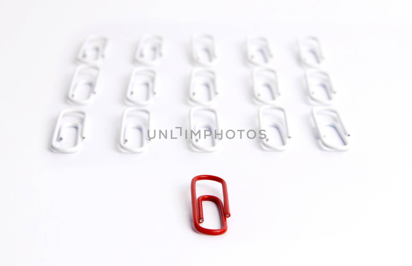 Conceptual idea of leadership. Red clip in focus, leading a group of aligned white clips