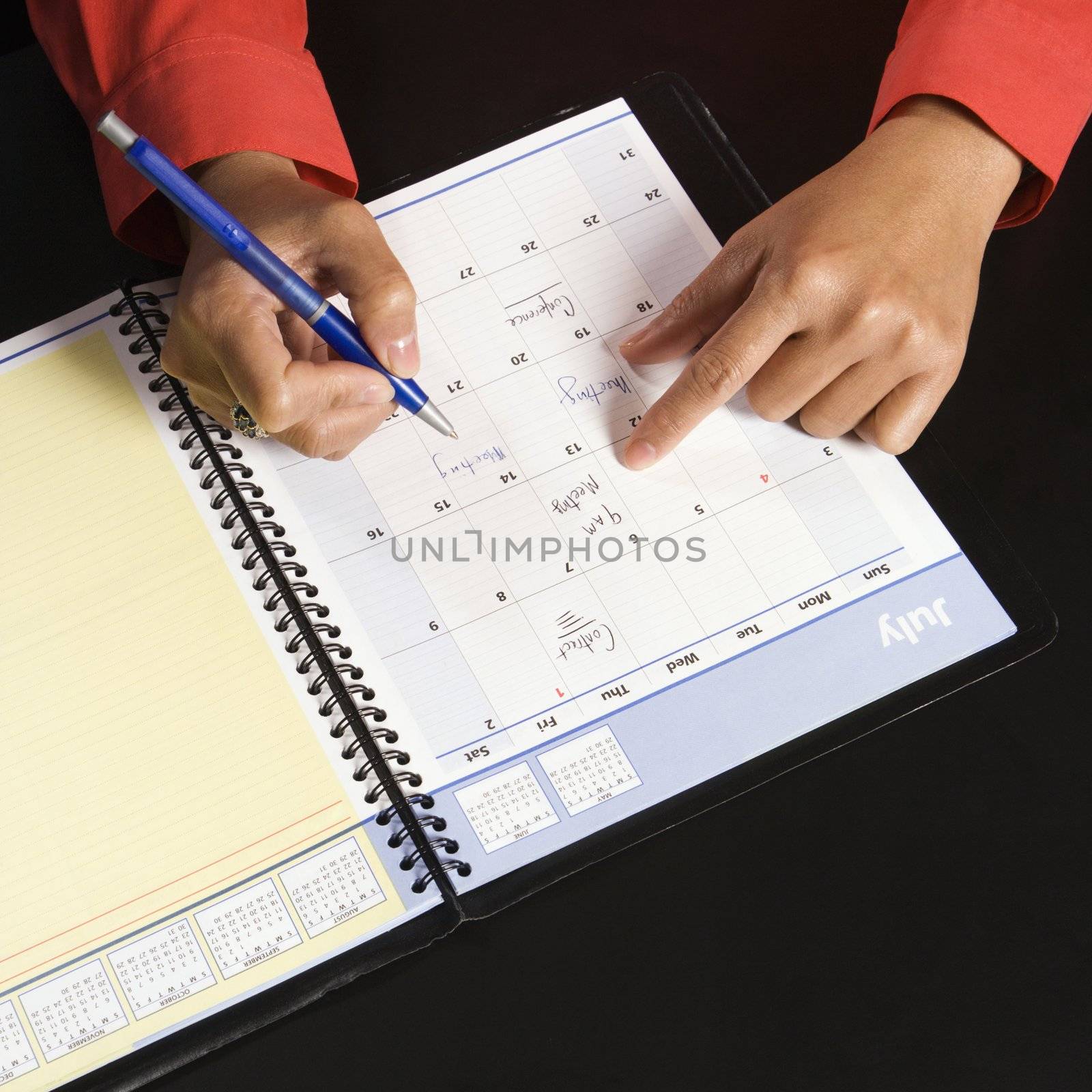 Businesswoman writing in appointment calendar.