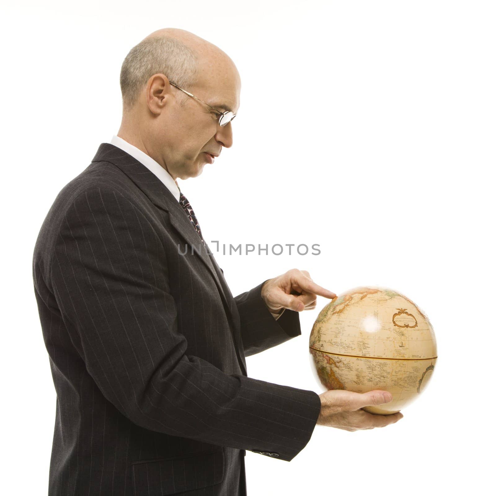 Caucasian middle-aged businessman holding globe and pointing standing in front of white background.