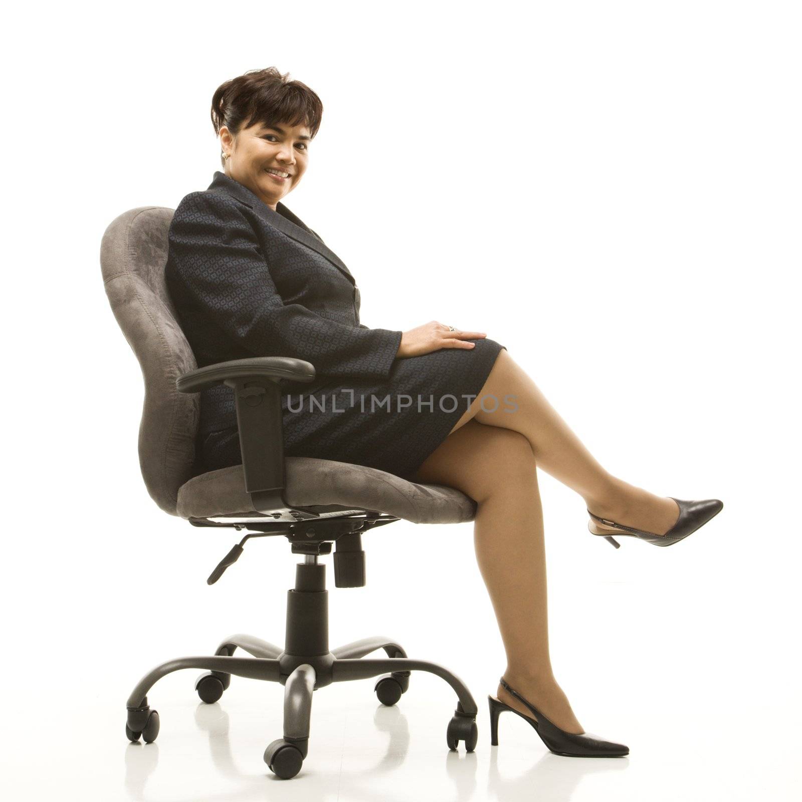 Filipino middle-aged businesswoman sitting in office chair against white background.