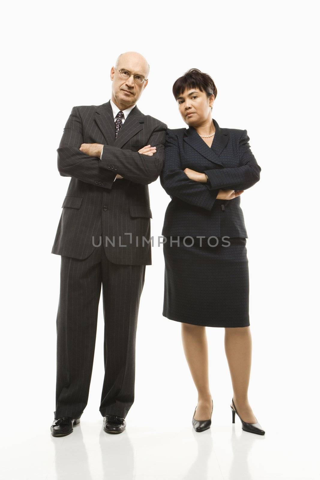 Caucasian middle-aged businessman and Filipino businesswoman standing with arms crossed against white background.