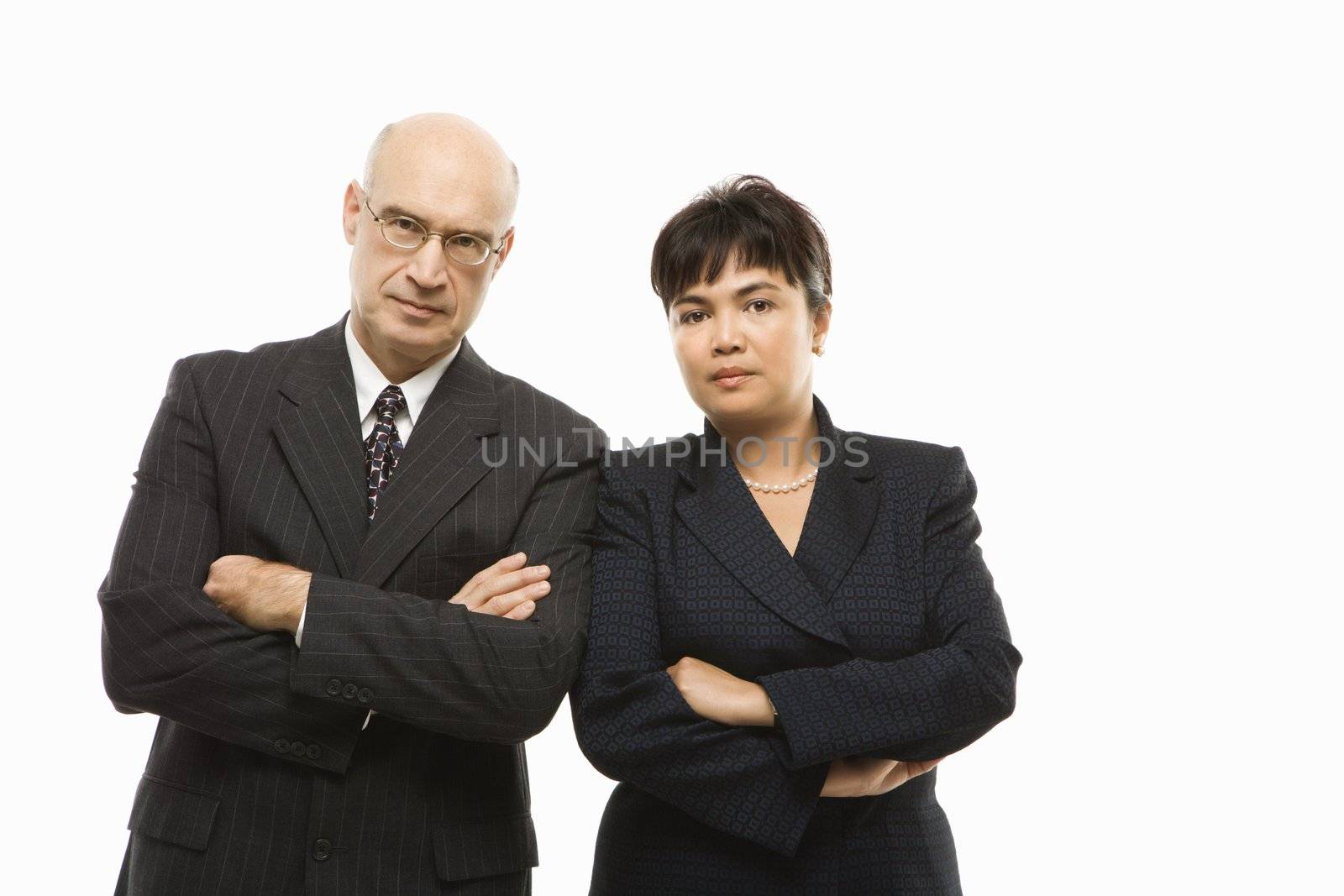 Caucasian middle-aged businessman and Filipino businesswoman standing with arms crossed against white background.