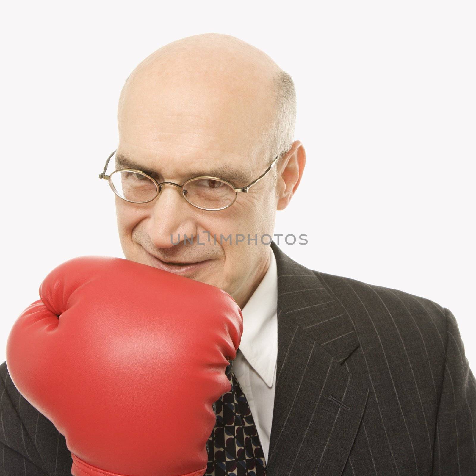 Caucasian middle-aged businessman holding up arm wearing boxing glove.