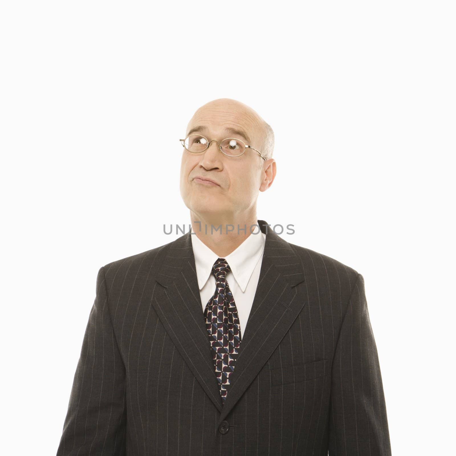 Caucasian middle-aged businessman looking indecisive standing against white background.