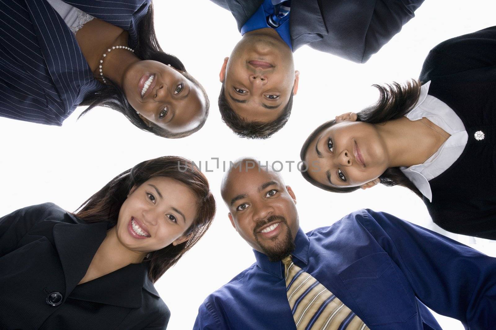 Low angle portrait of multi-ethnic business group of men and women in huddle looking at viewer.