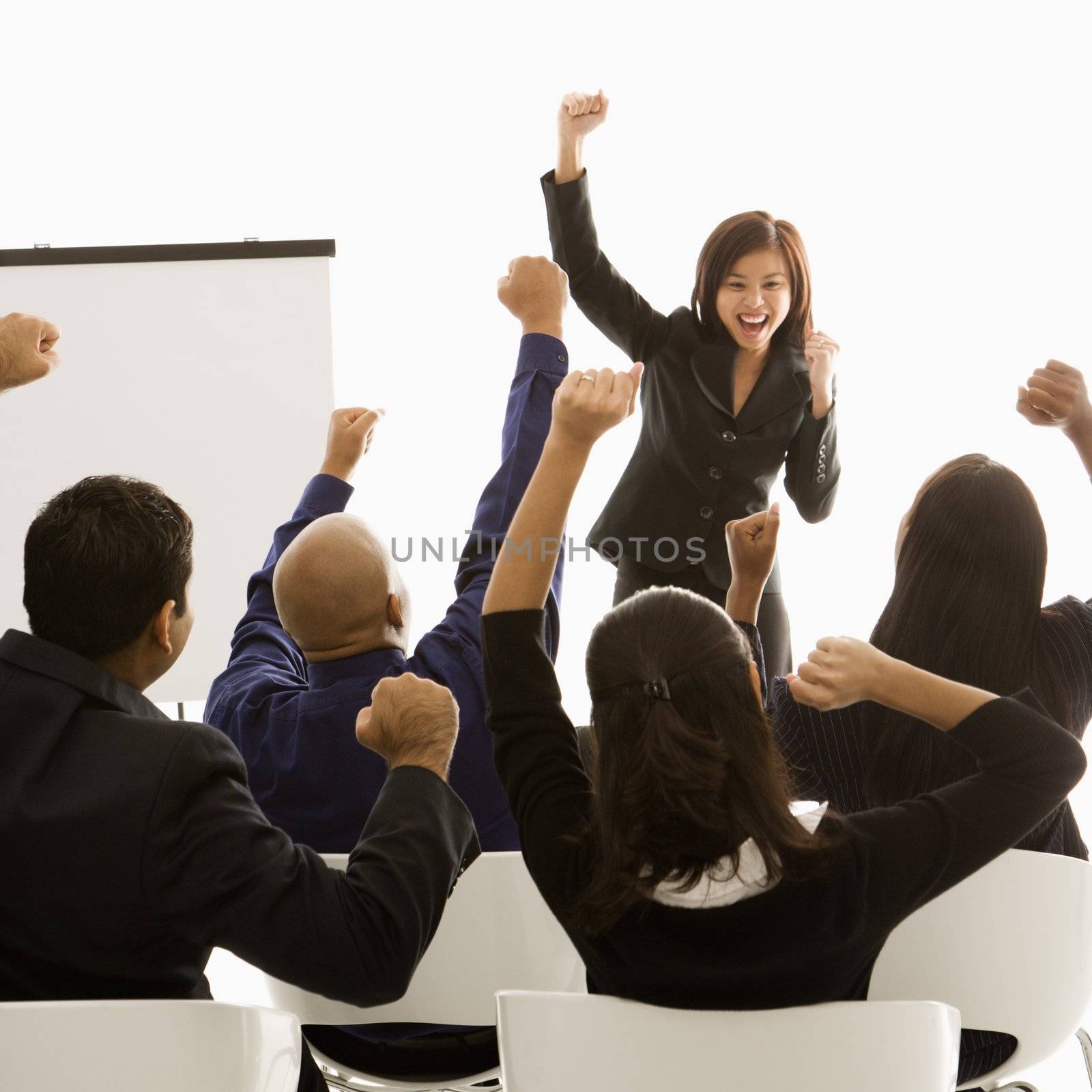 Vietnamese mid-adult woman standing in front of cheering business group during a presentation.