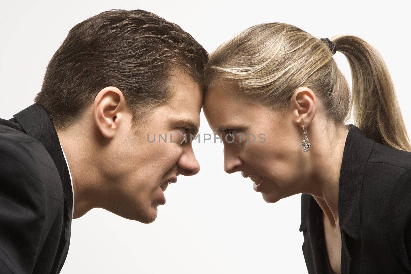 Caucasian mid-adult man and woman with foreheads together staring at each other with hostile expressions.