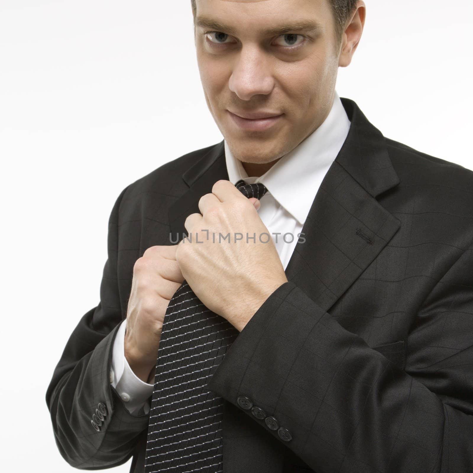 Caucasian mid-adult man straightening necktie.