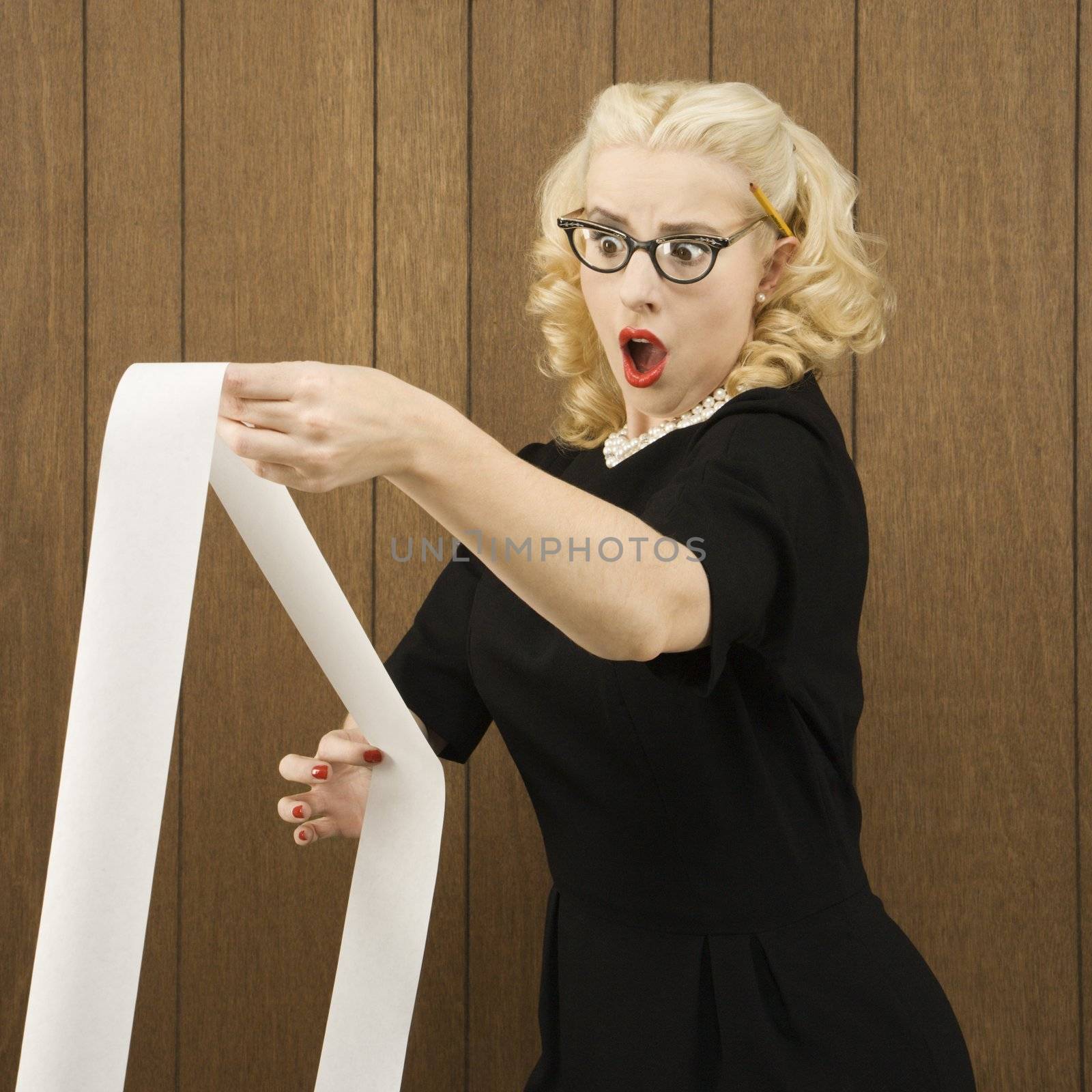 Mid-adult Caucasian female in vintage outfit holding a printout with a shocking expression on her face.