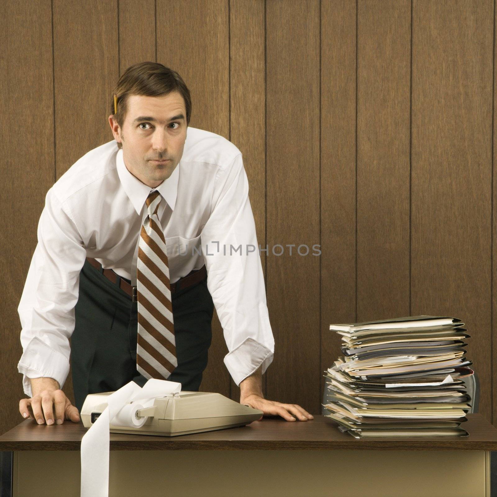 Mid-adult Caucasian male with hands on desk.