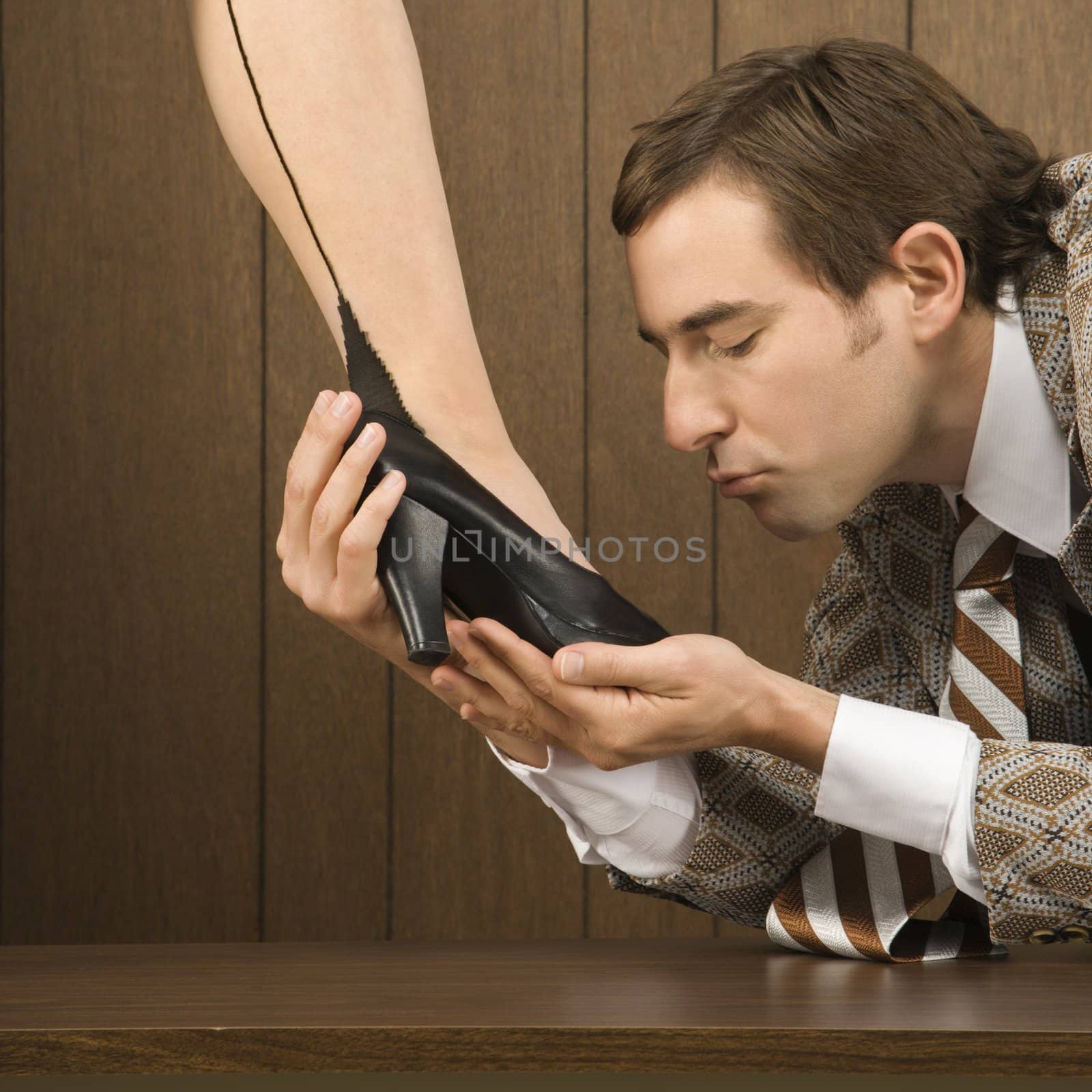 Mid-adult Caucasian male holding Caucasian female shoe and preparing to kiss it.