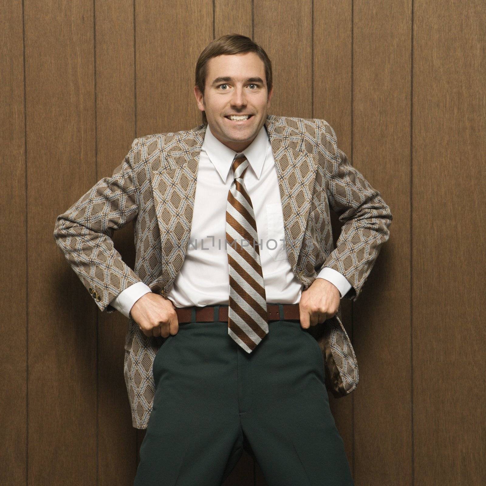 Mid-adult smiling Caucasian male in retro suit pulling up on pants.