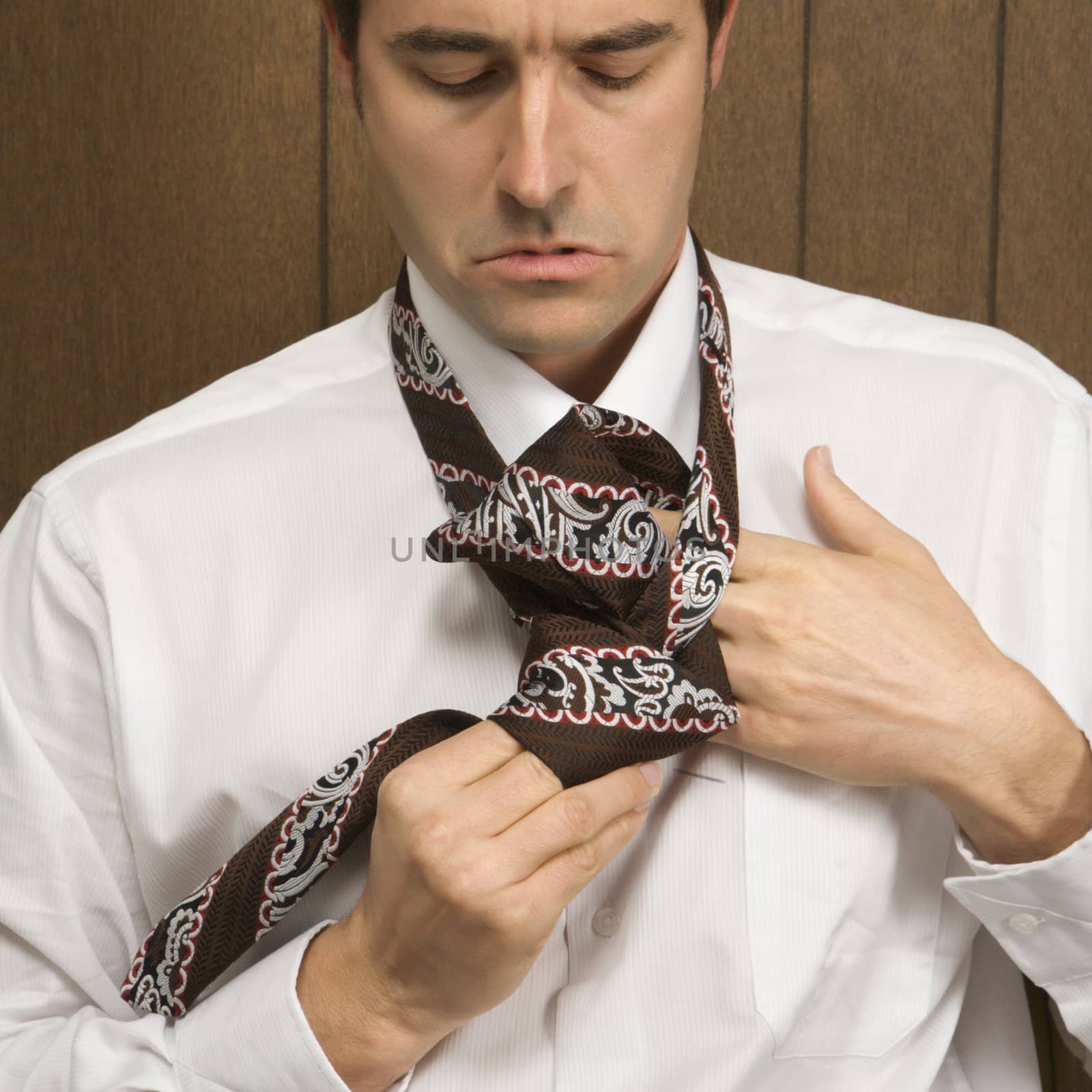 Mid-adult Caucasian male tying his necktie.