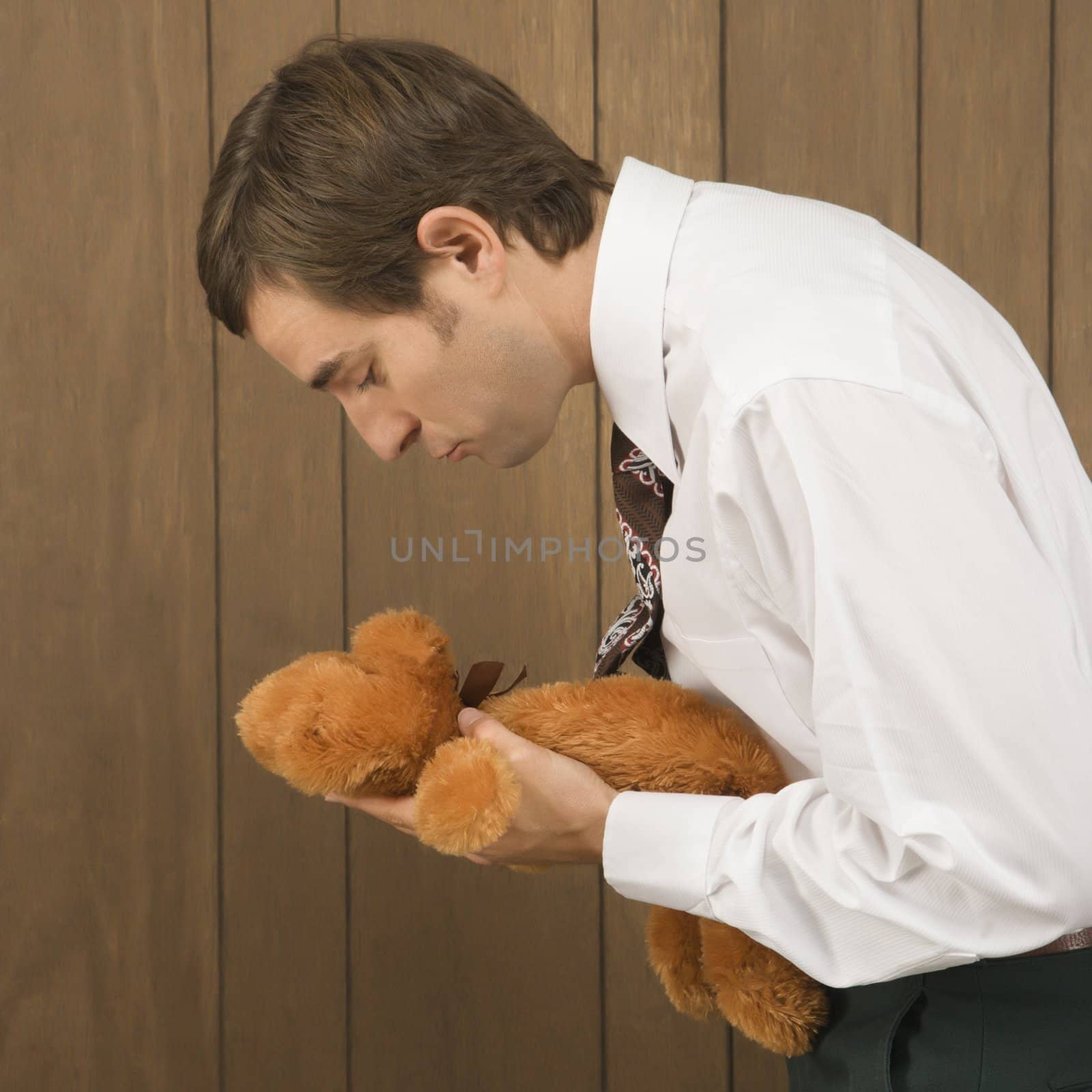 Mid-adult Caucasian male holding a stuffed animal preparing to kiss it.