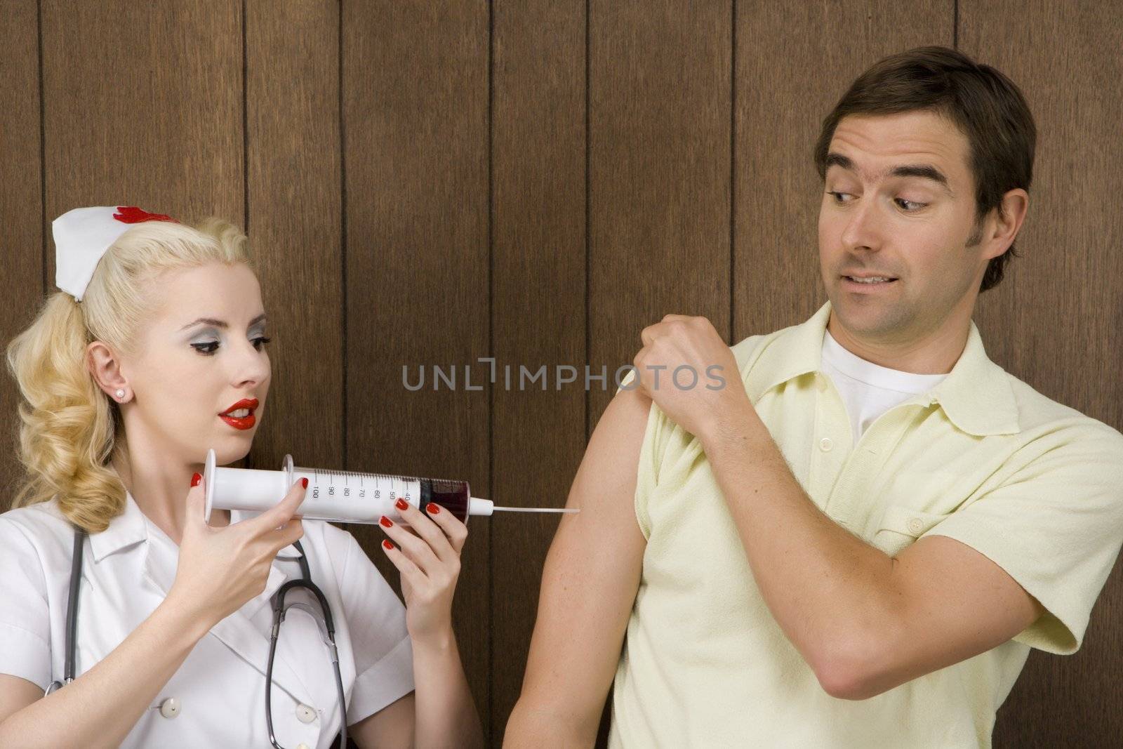 Caucasian mid-adult female nurse giving shot to man with oversized syringe.