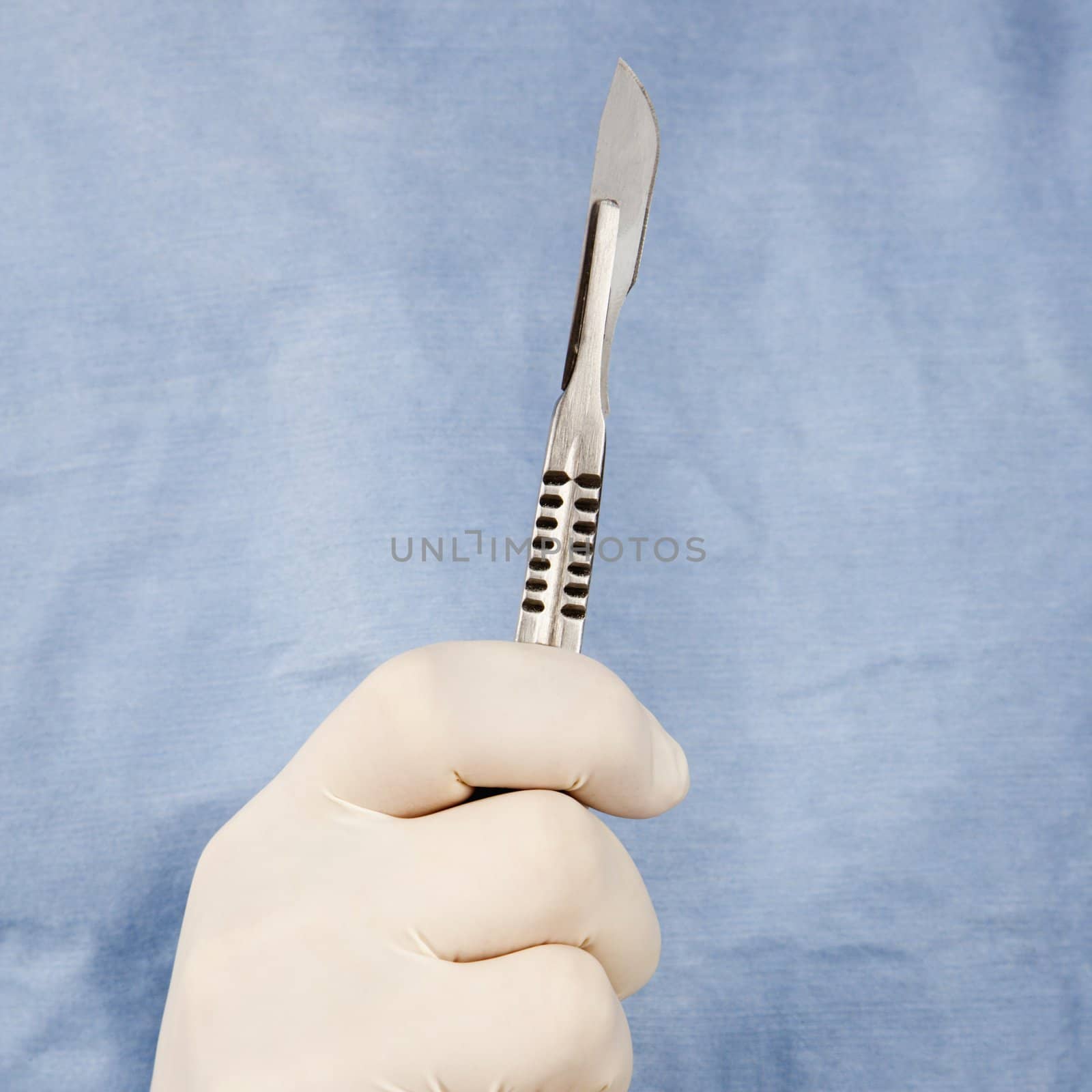 Close-up of male surgeon's gloved hand holding scalpel.