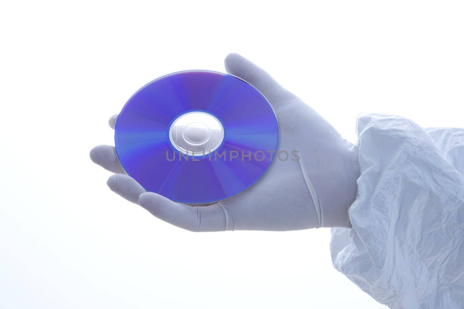 Hand in latex glove holding disc against white background.