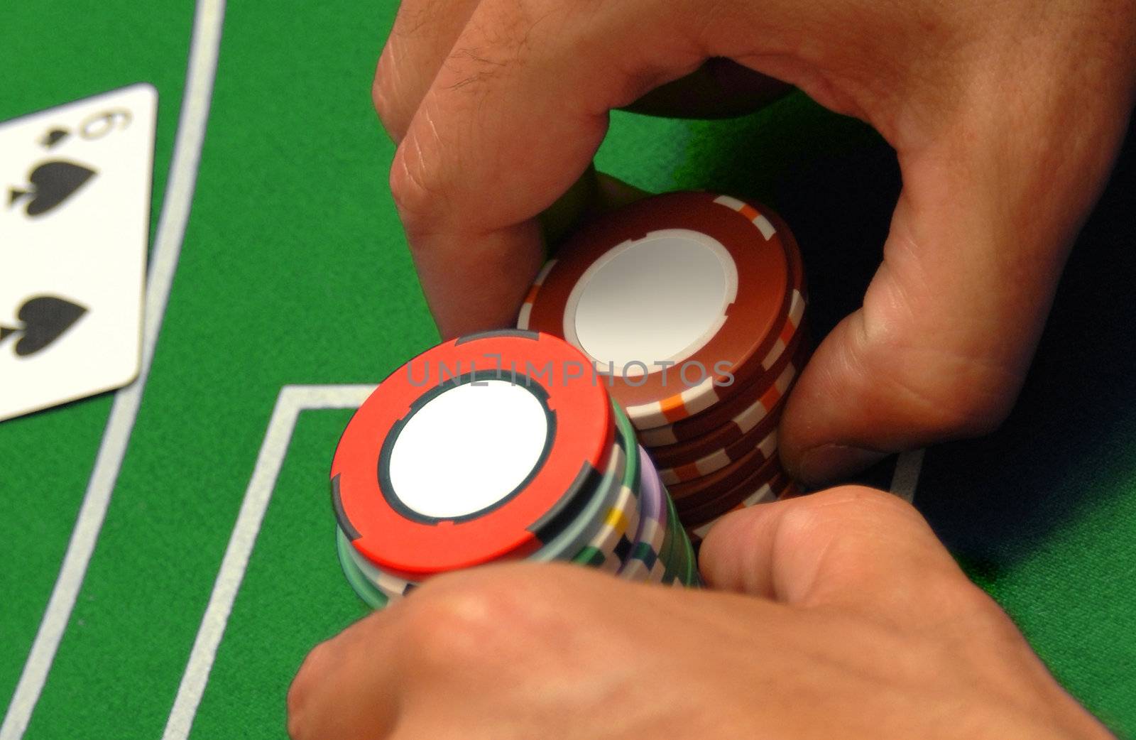 Casino chips for poker, blackjack or other table game. Male hands of a gambler on green background.