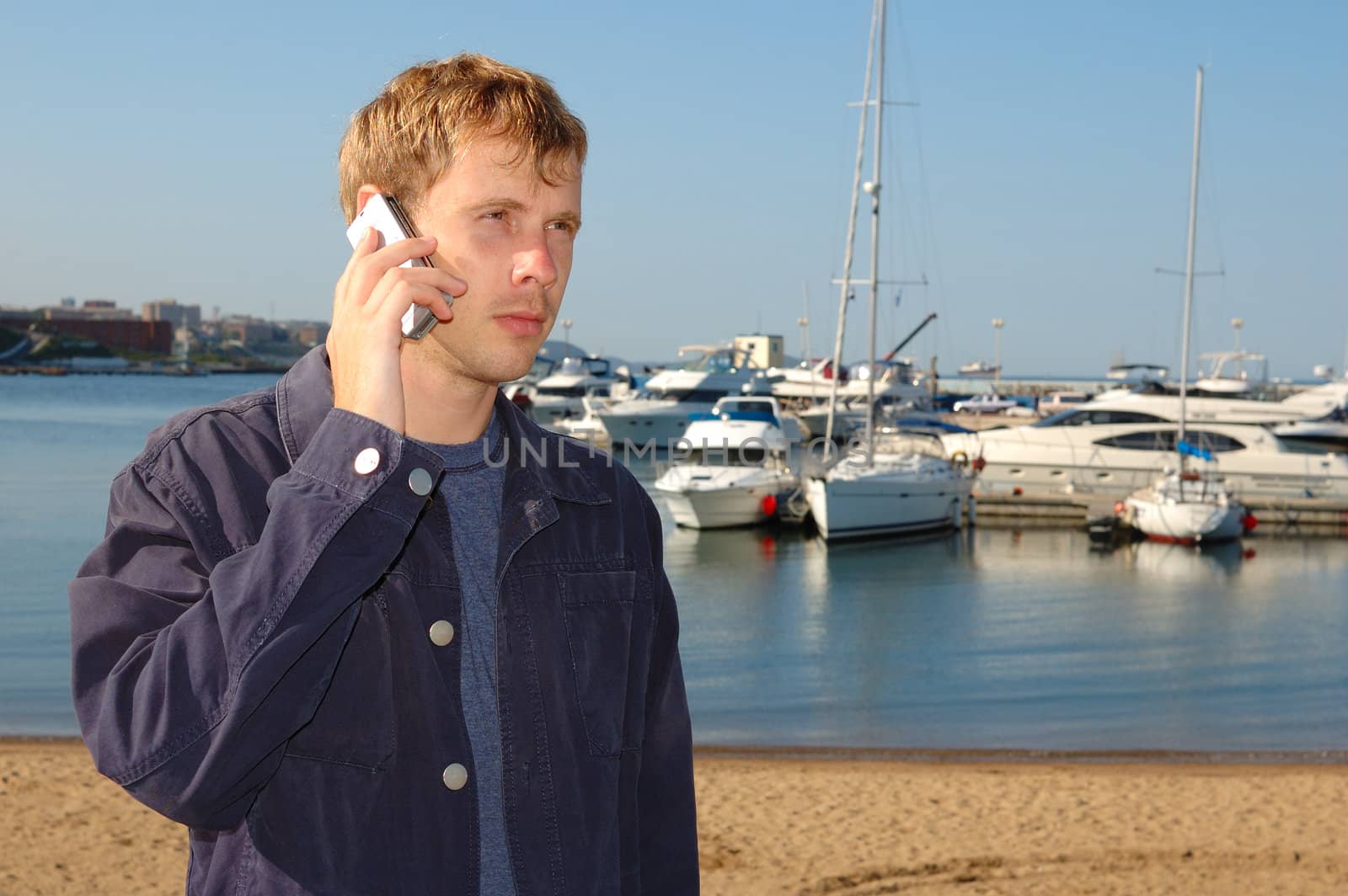 Young stylish man talk on mobile phone with yacht background.