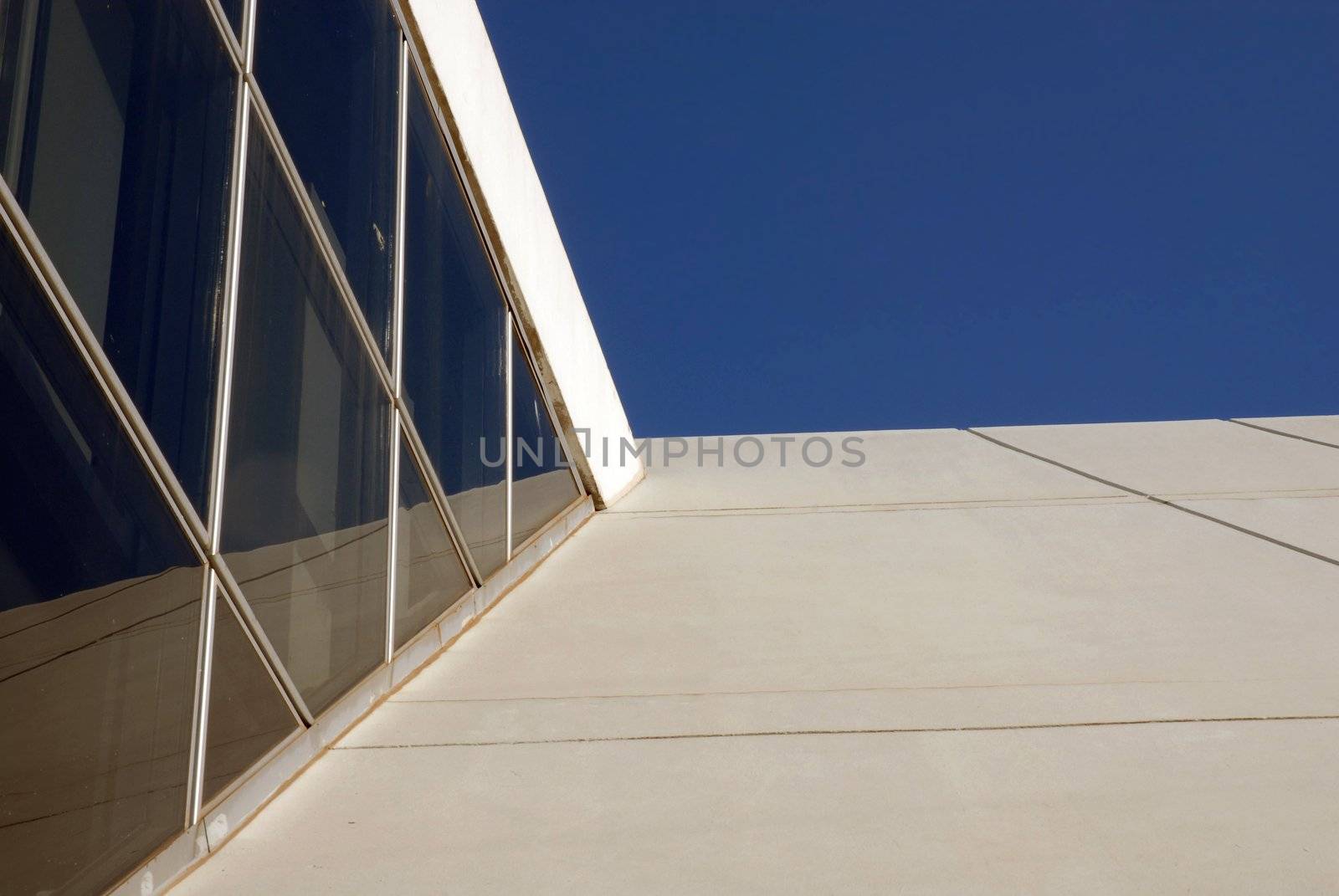 Architectural detail of a contemporary building reflecting on a blue sky background. Bottom view