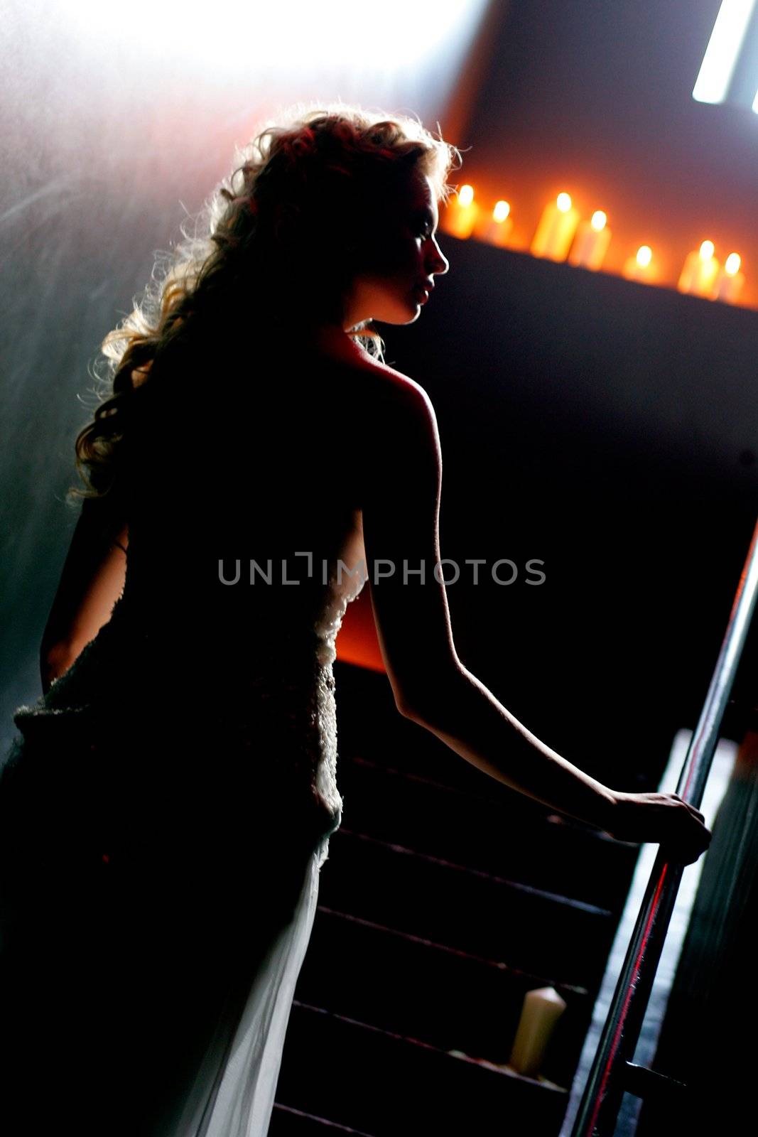 Silhouette of a beautiful bride in a traditional white wedding dress, walking in candlelit church.