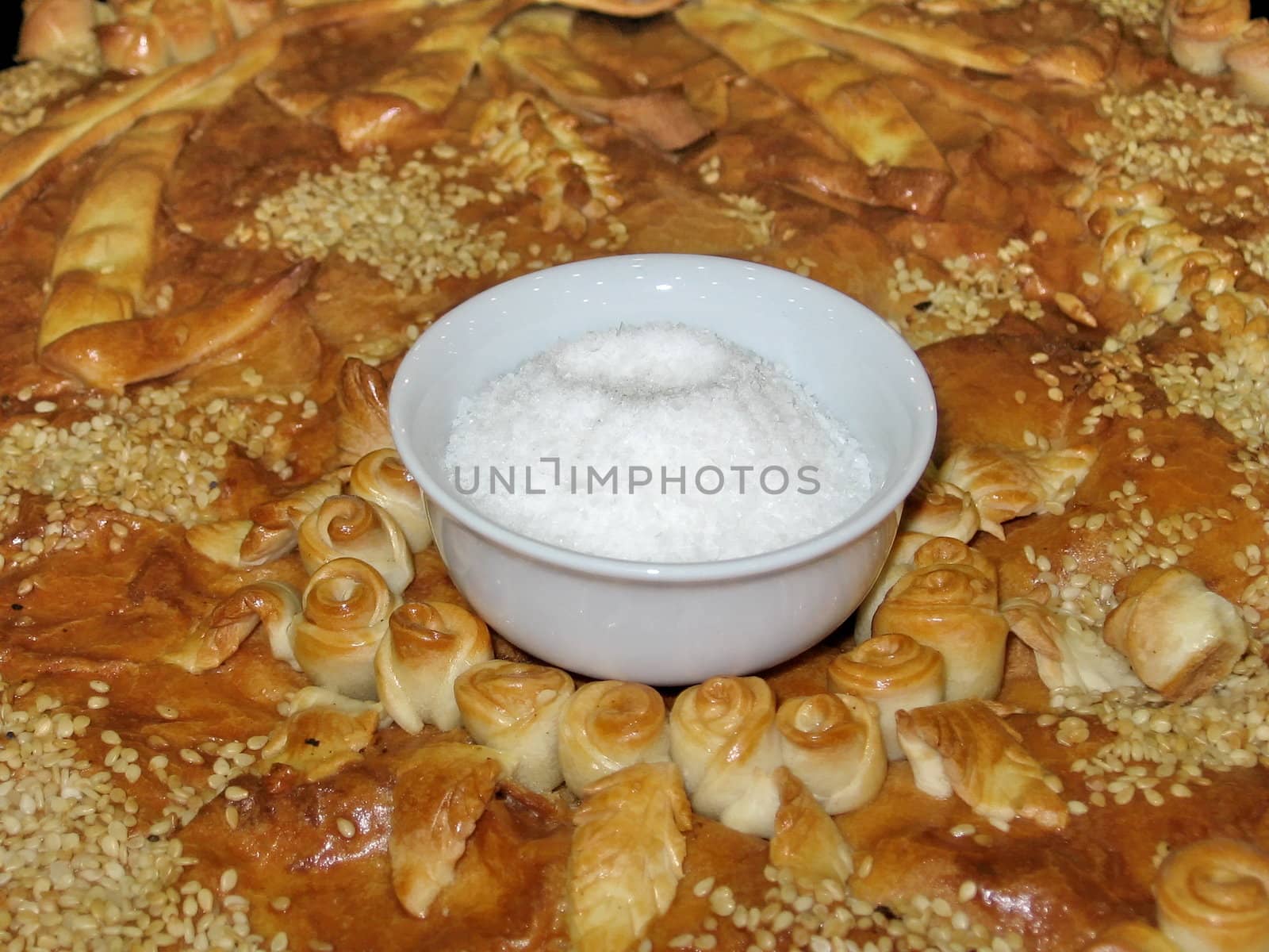 White saltcellar with salt on a background of tasty cake