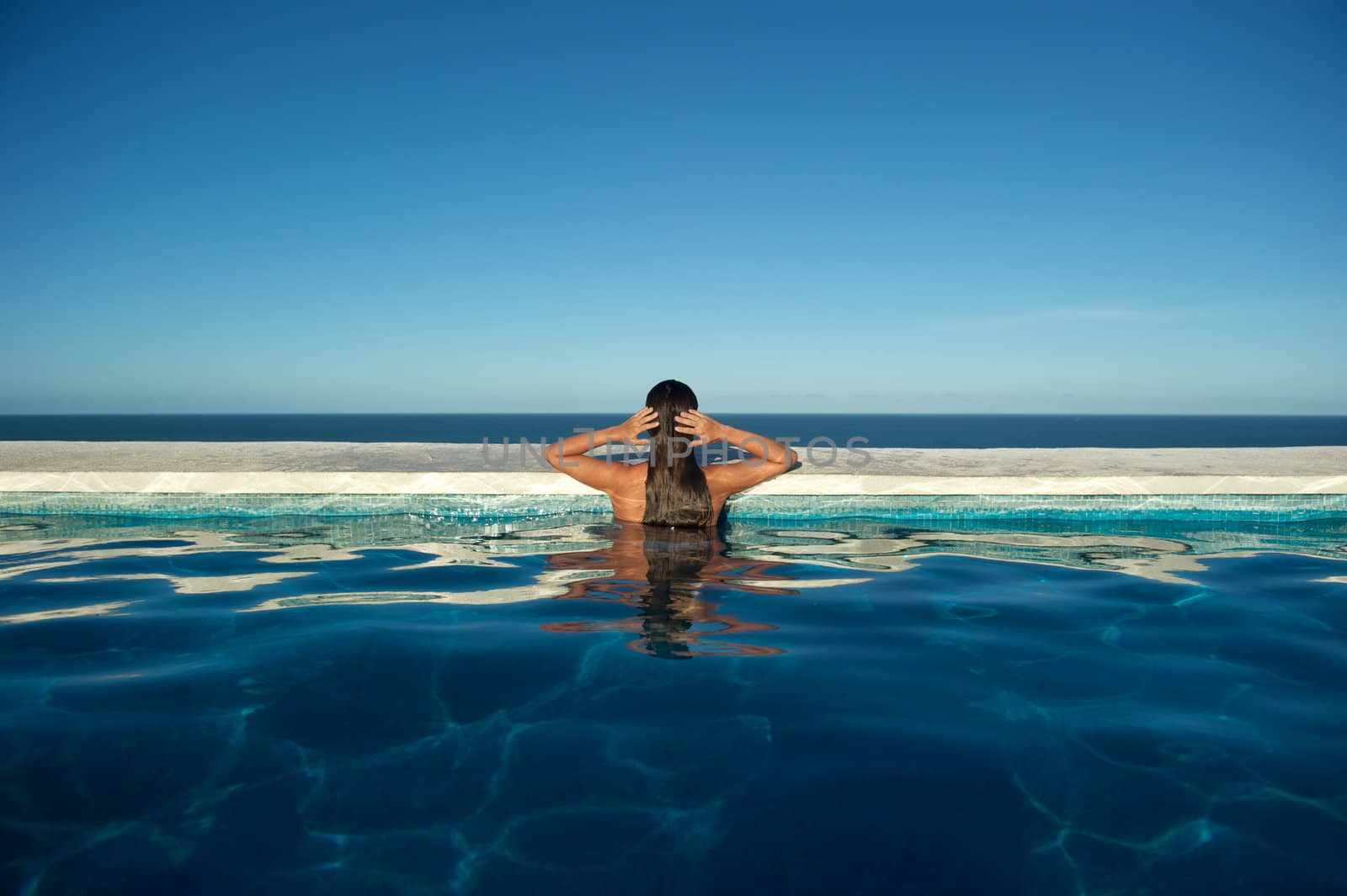 Woman relaxing on a swimming pool with a sea view in Arraial d'Ajuda, Bahia, Brazil, Nikon D3S, RAW shooting.