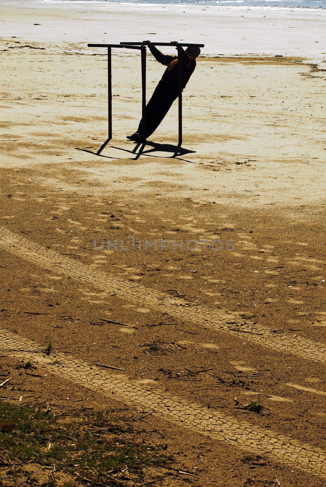 Man doing parallel bars on the beach by cienpies