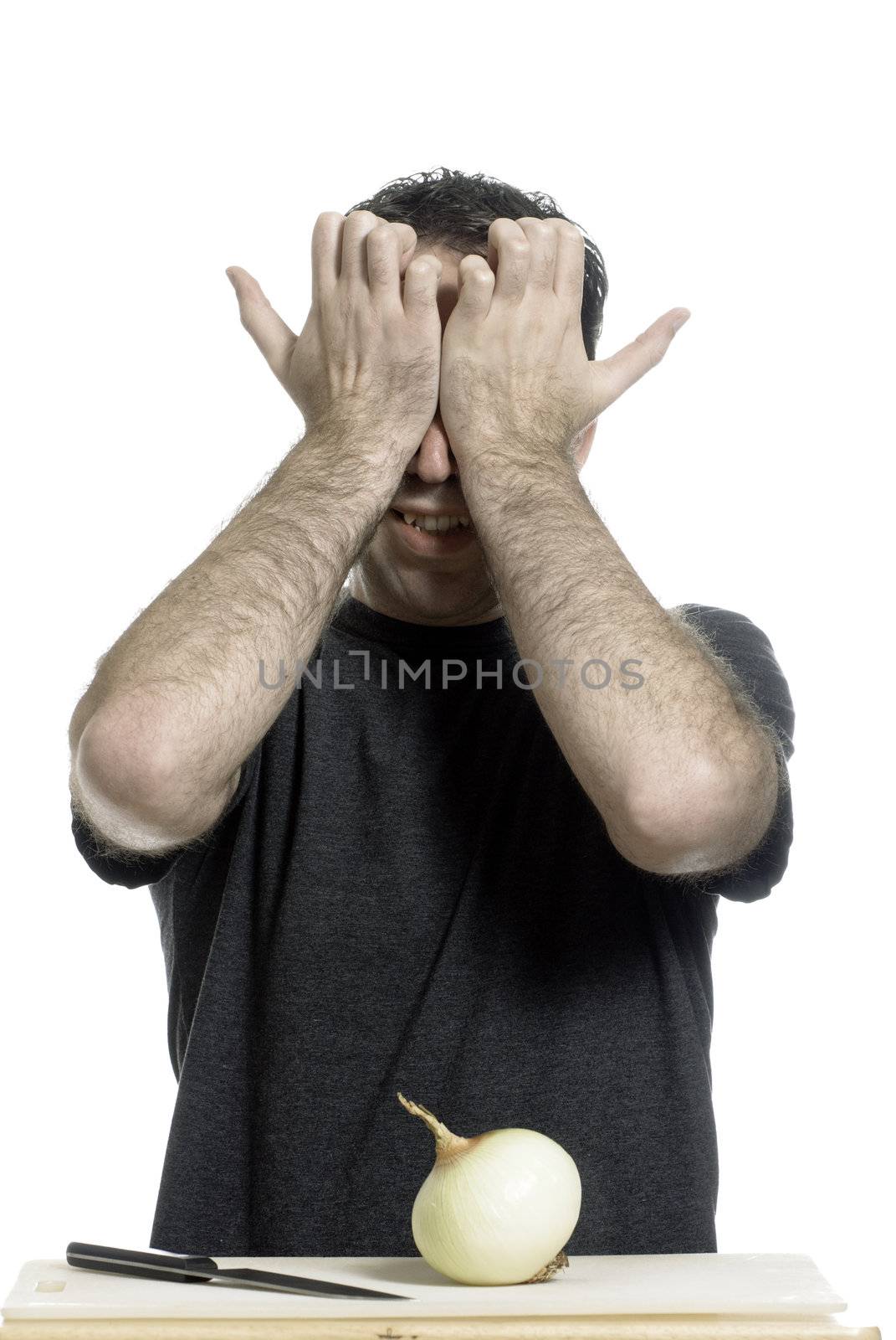A young man holding his eyes in pain without even starting to cut the onion, isolated against a white background