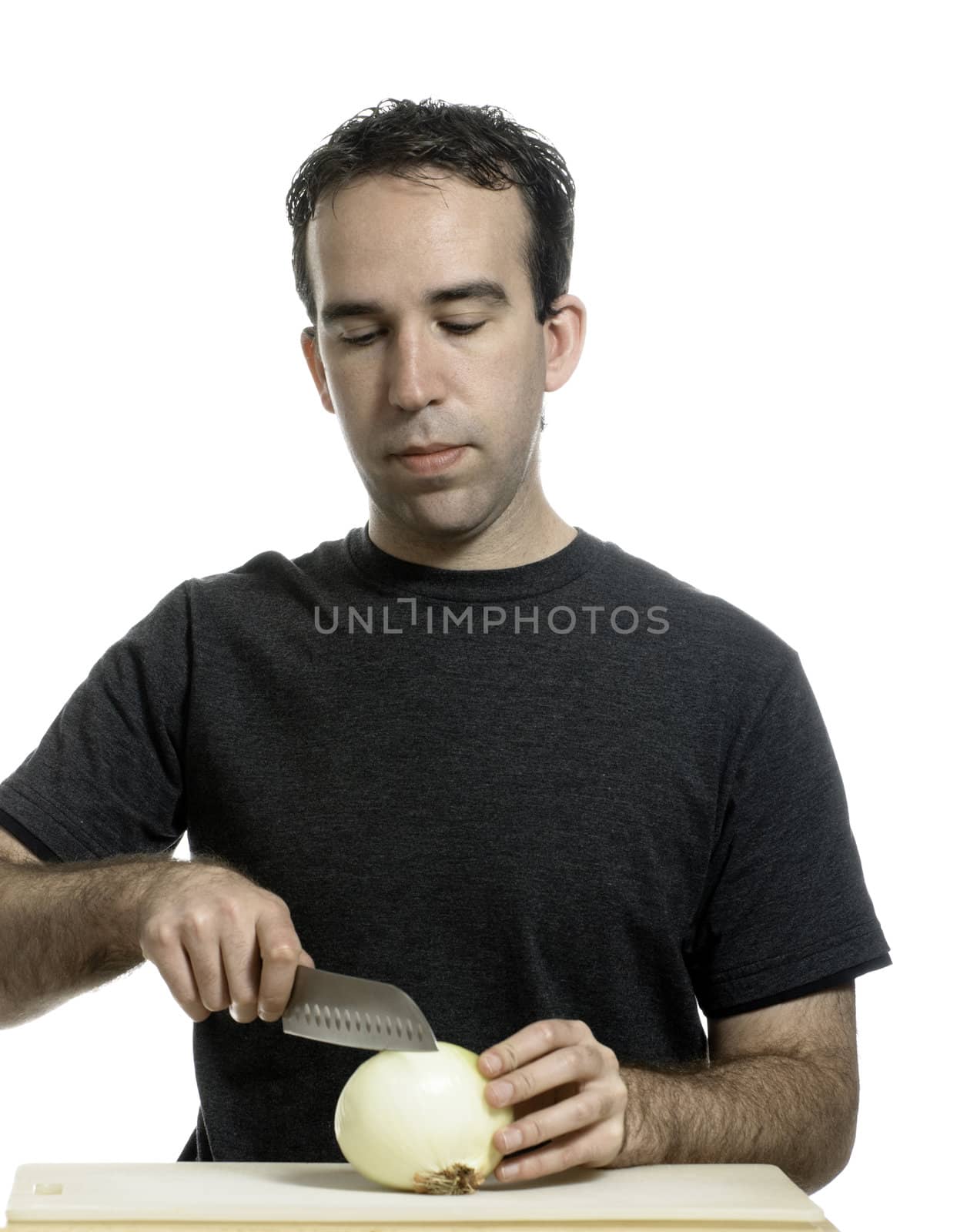 A young man cutting an onion with a sharp knife, isolated against a white background