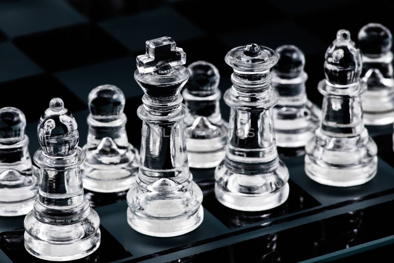 Glass chess pieces in start position on glass board