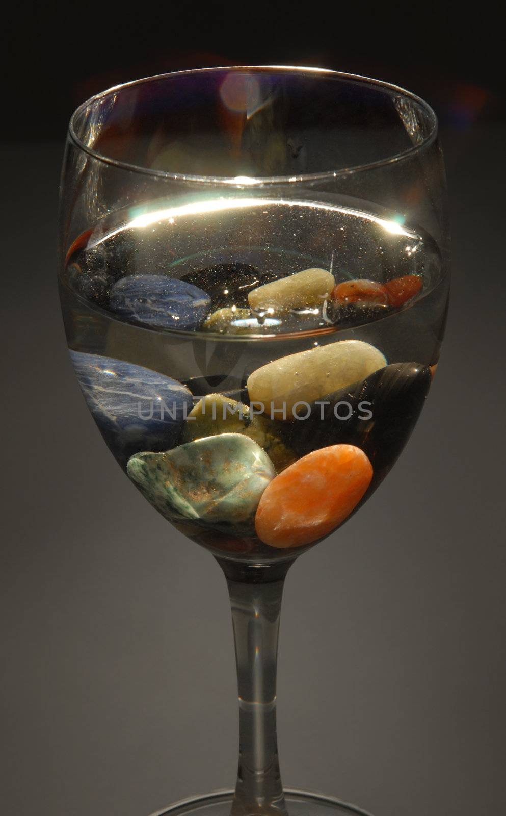 Colored stones in a glass of water by cienpies