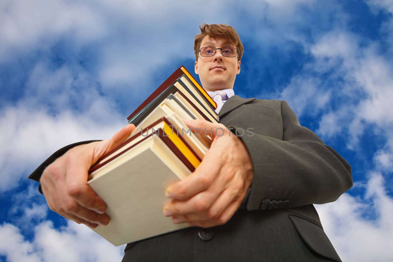 A man with a big stack of books against the sky