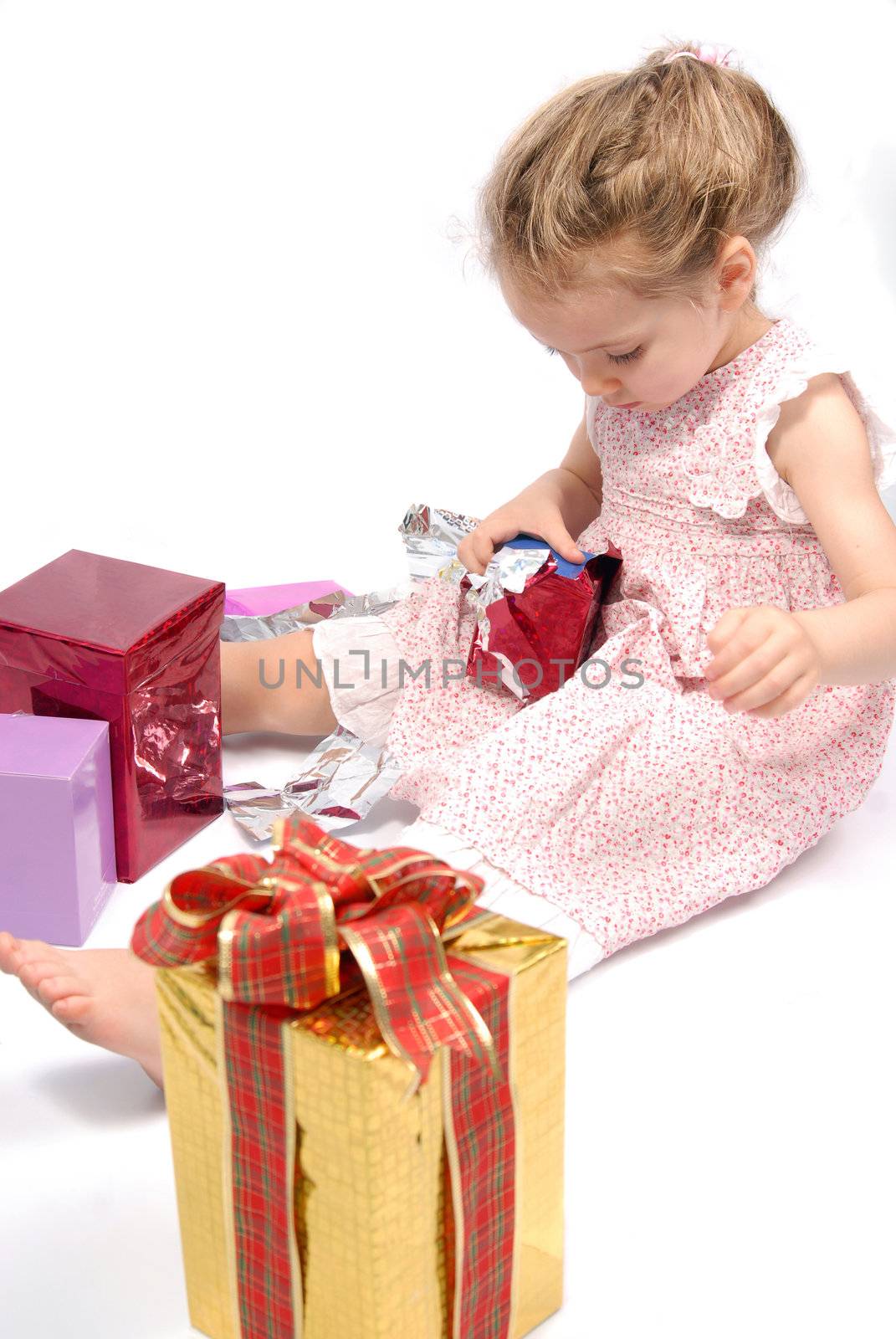 Little girl opening her colorful Christmas presents. White background