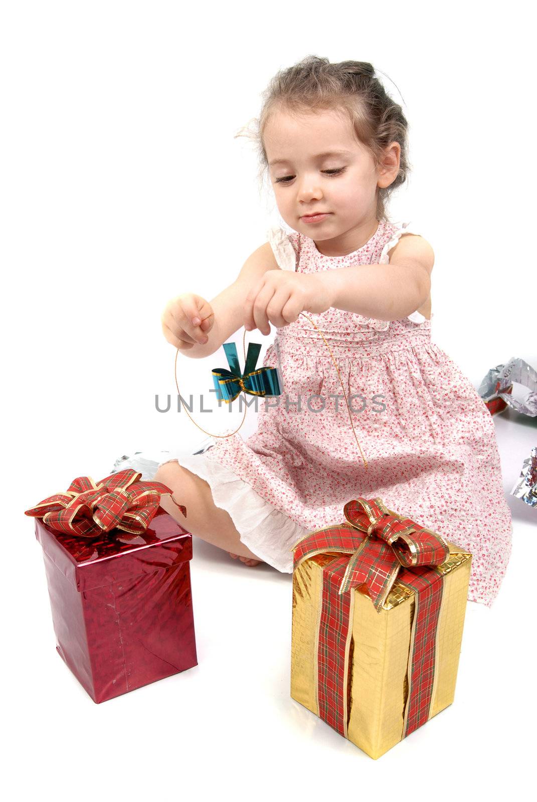 Little girl about to open her Christmas presents, playing with a blue ribbon. White background