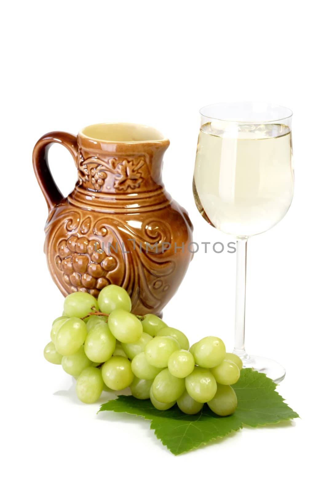 Glass of white wine with grapes, leaves and jug and on white background