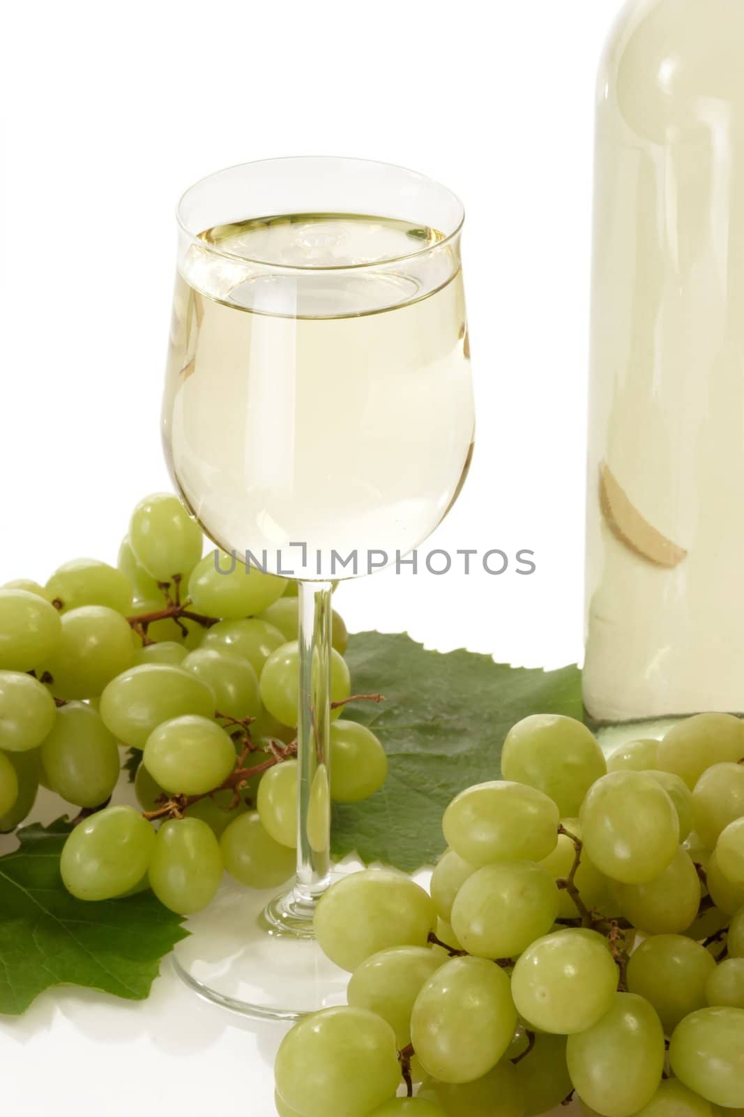 Glass of white wine with grapes and bottle on white background