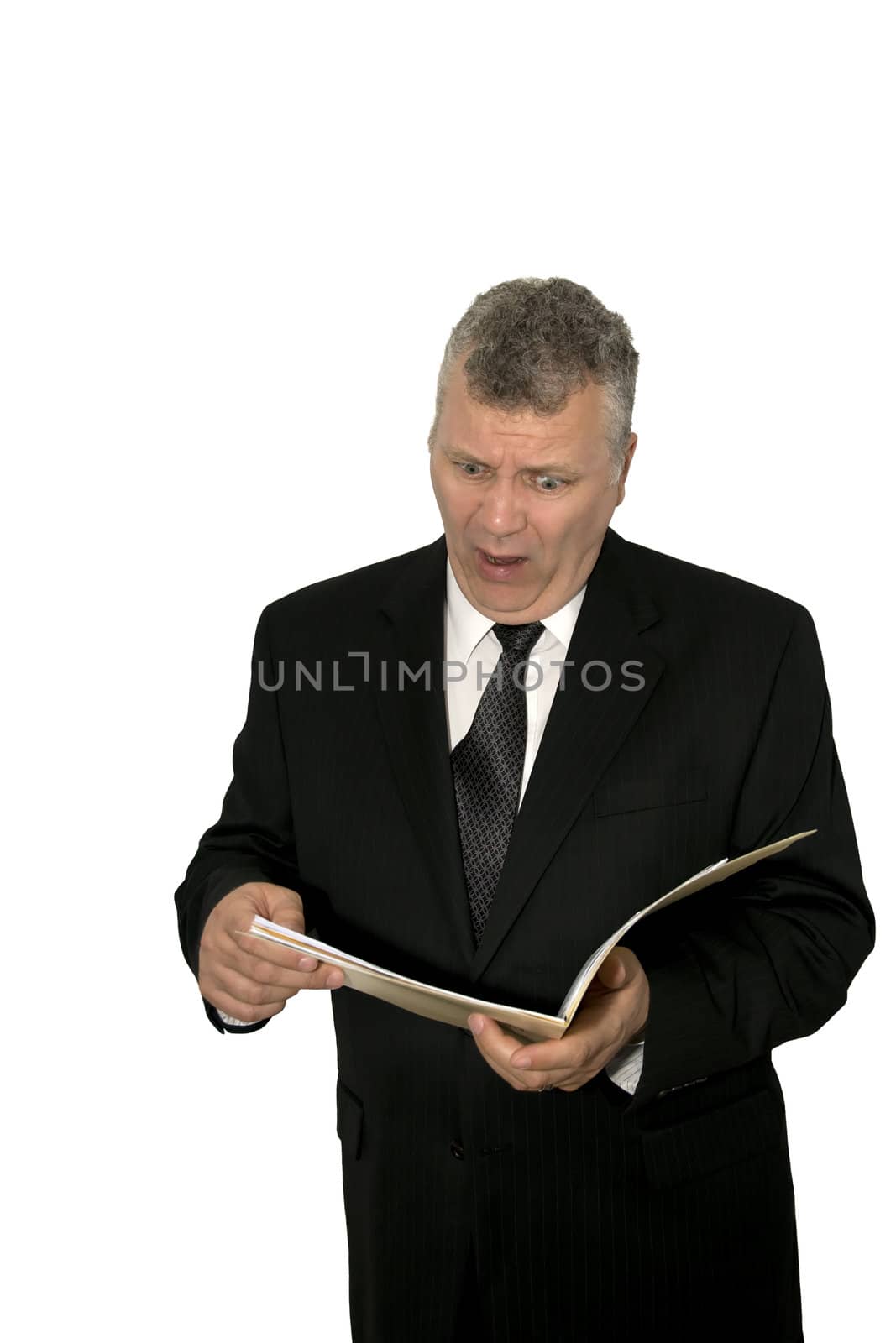 Businessman looking shocked while reading papers in a folder.