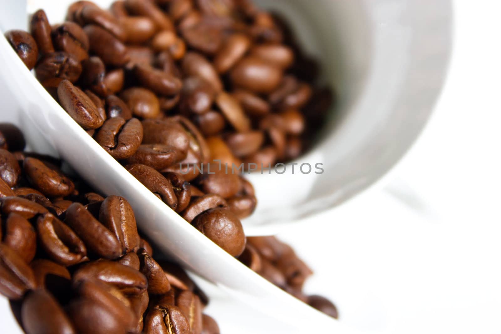 spilled coffee, coffee beans, porcelain saucer, white cup and saucer, fresh coffee beans