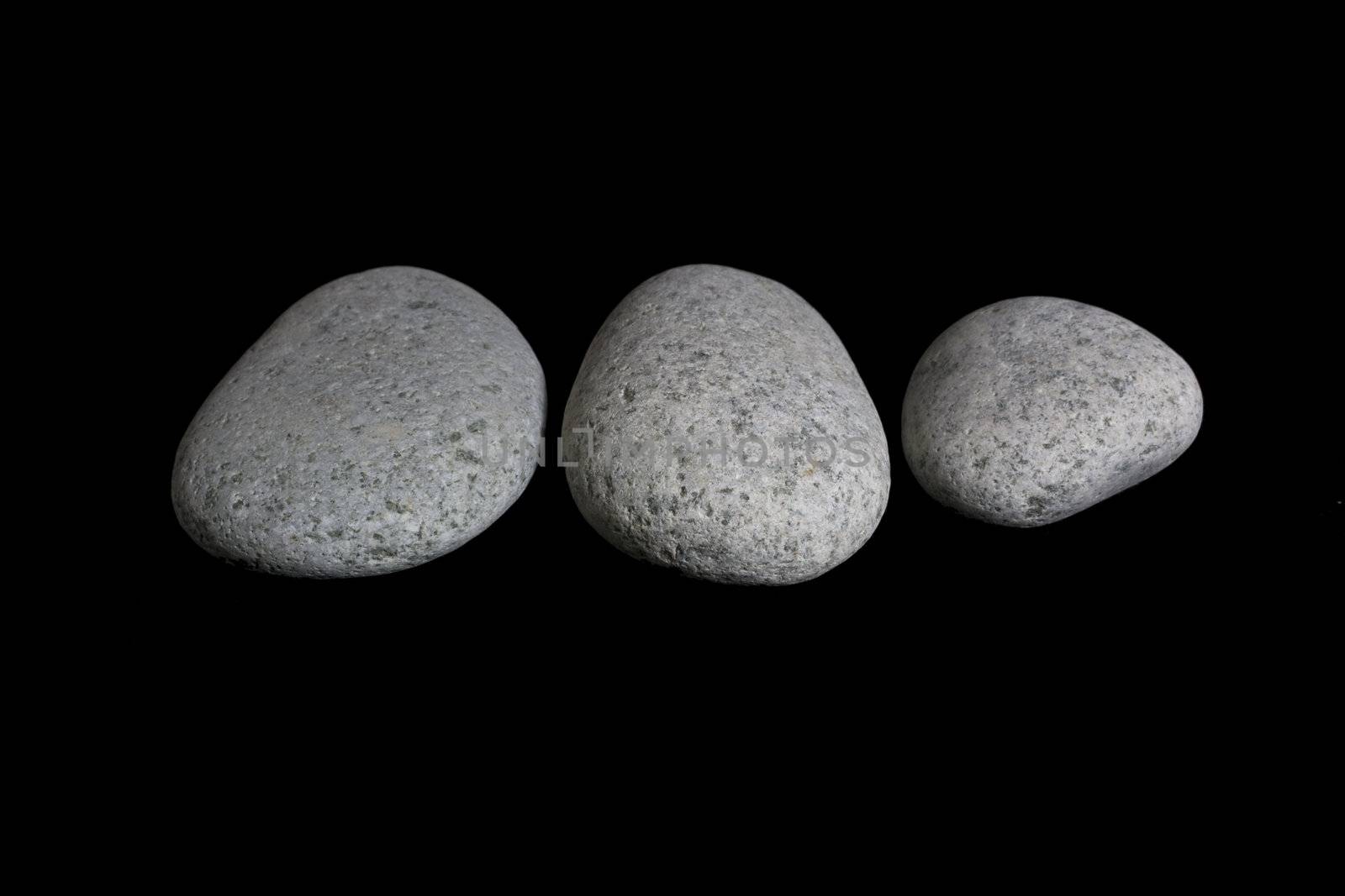 Three pebble stone against black background.