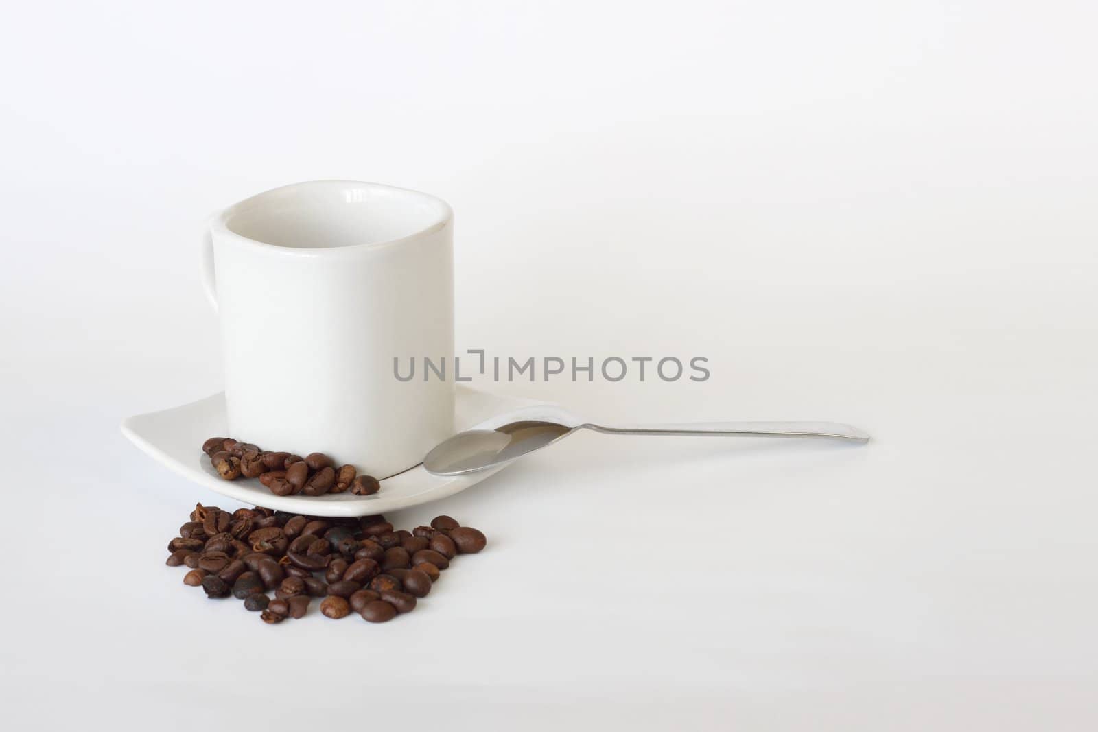 coffee mug, spoon and spilled coffee on white background