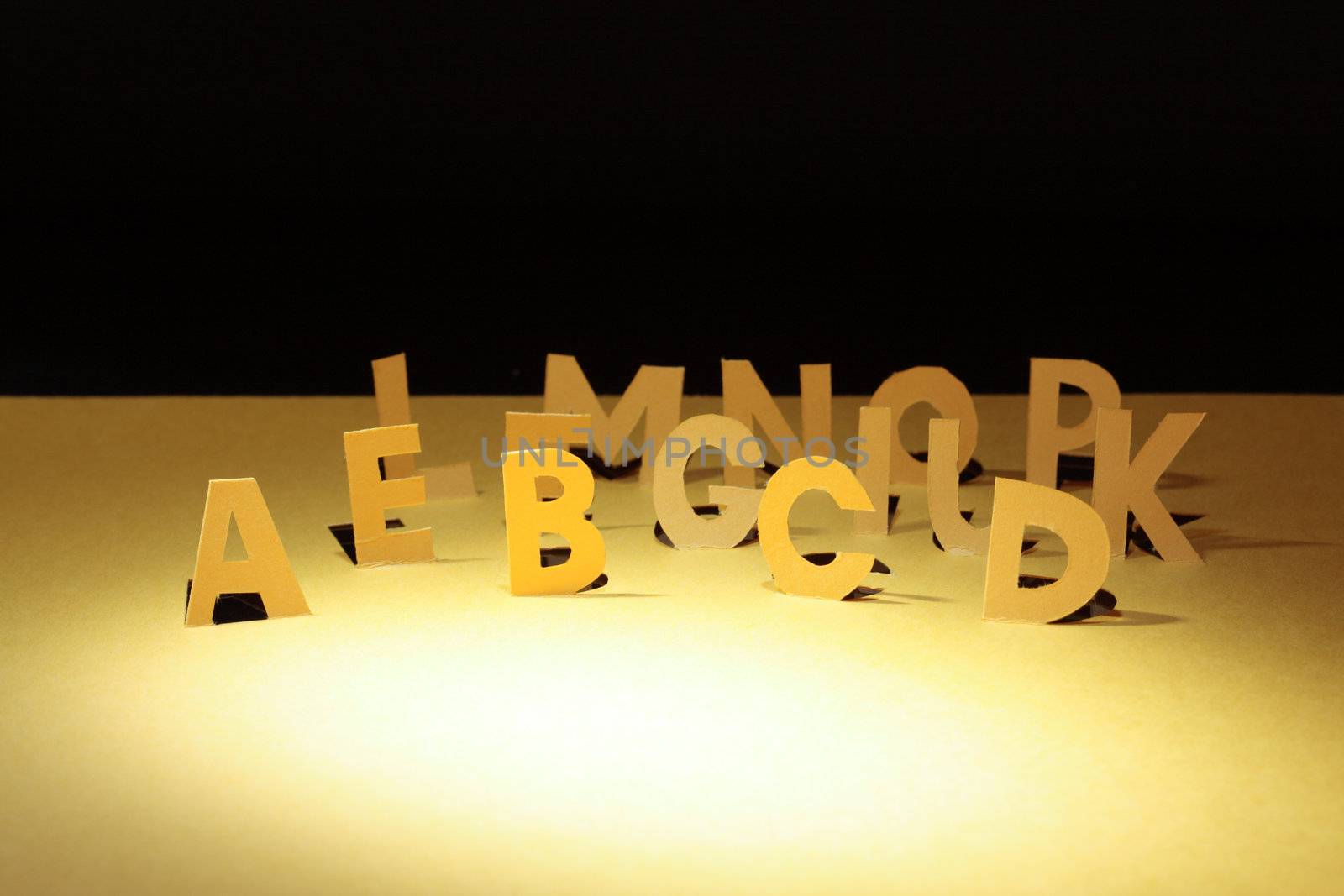 Letters cutting from yellow paper standing on dark background