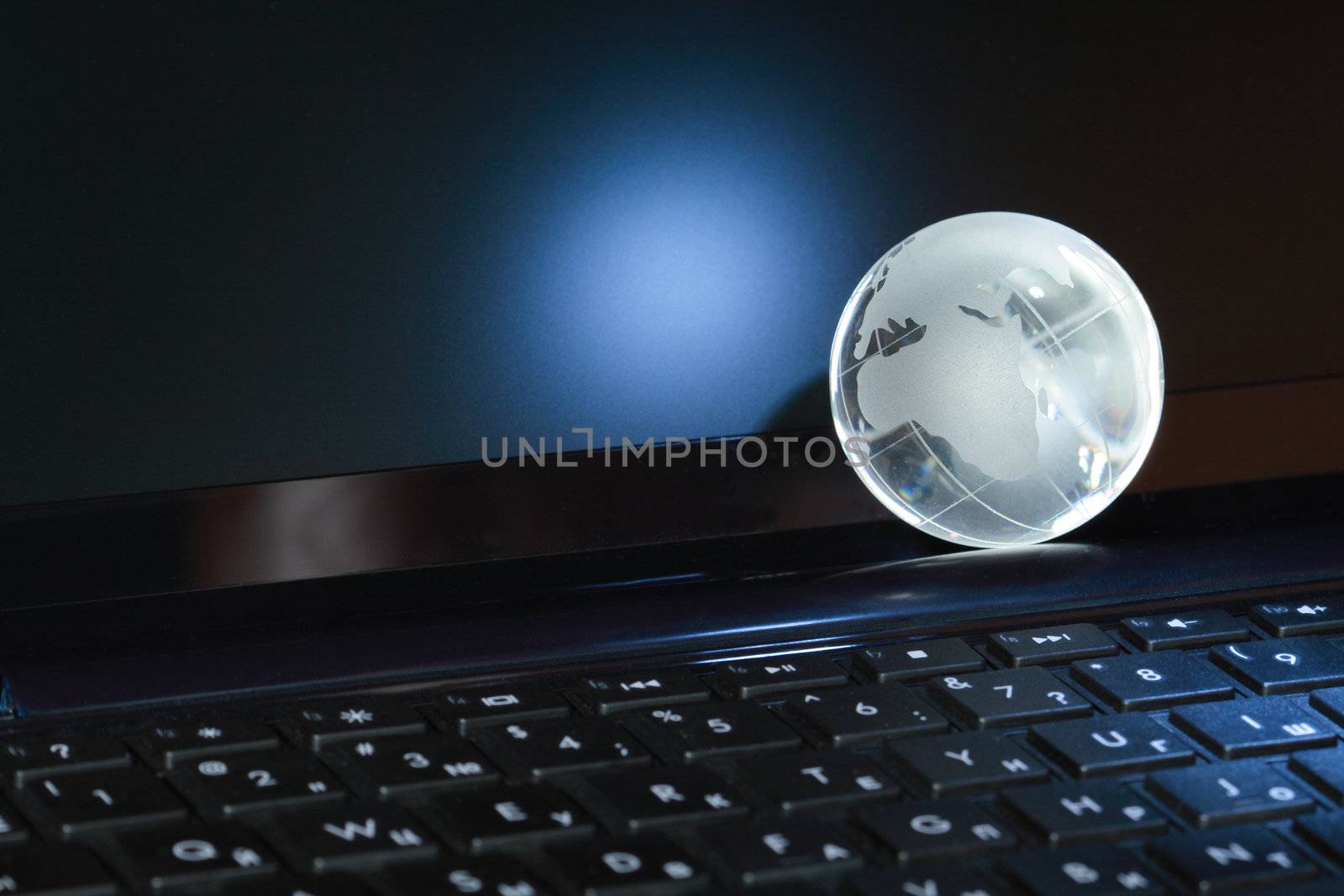 Closeup of glass globe lying on black computer keyboard