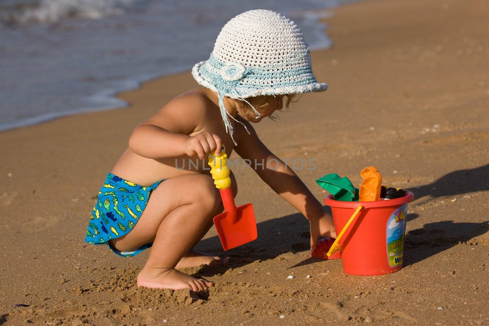 little girl in the bonnet plaing with sand, childhood