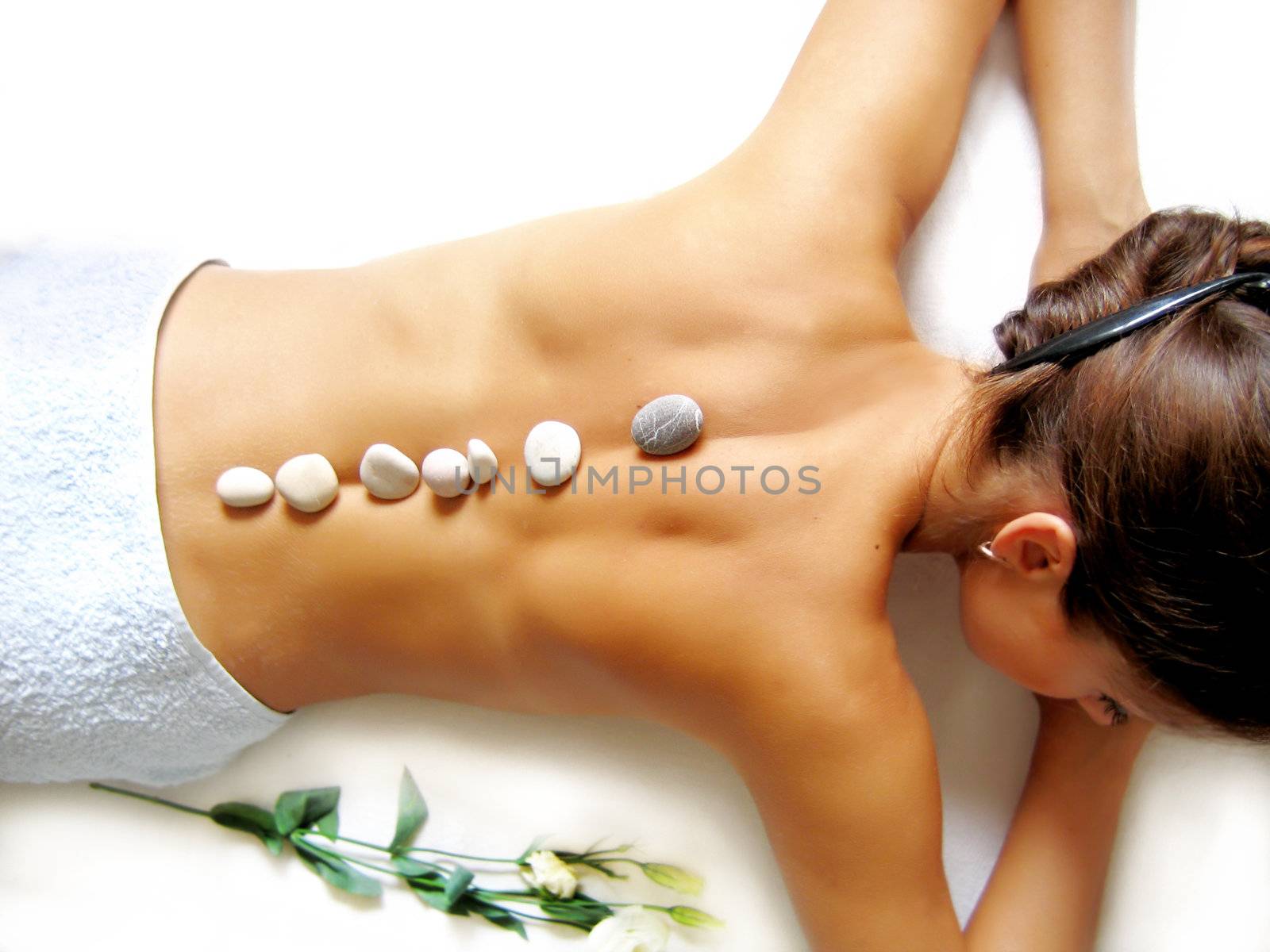 beautiful woman lying with stone massage on white