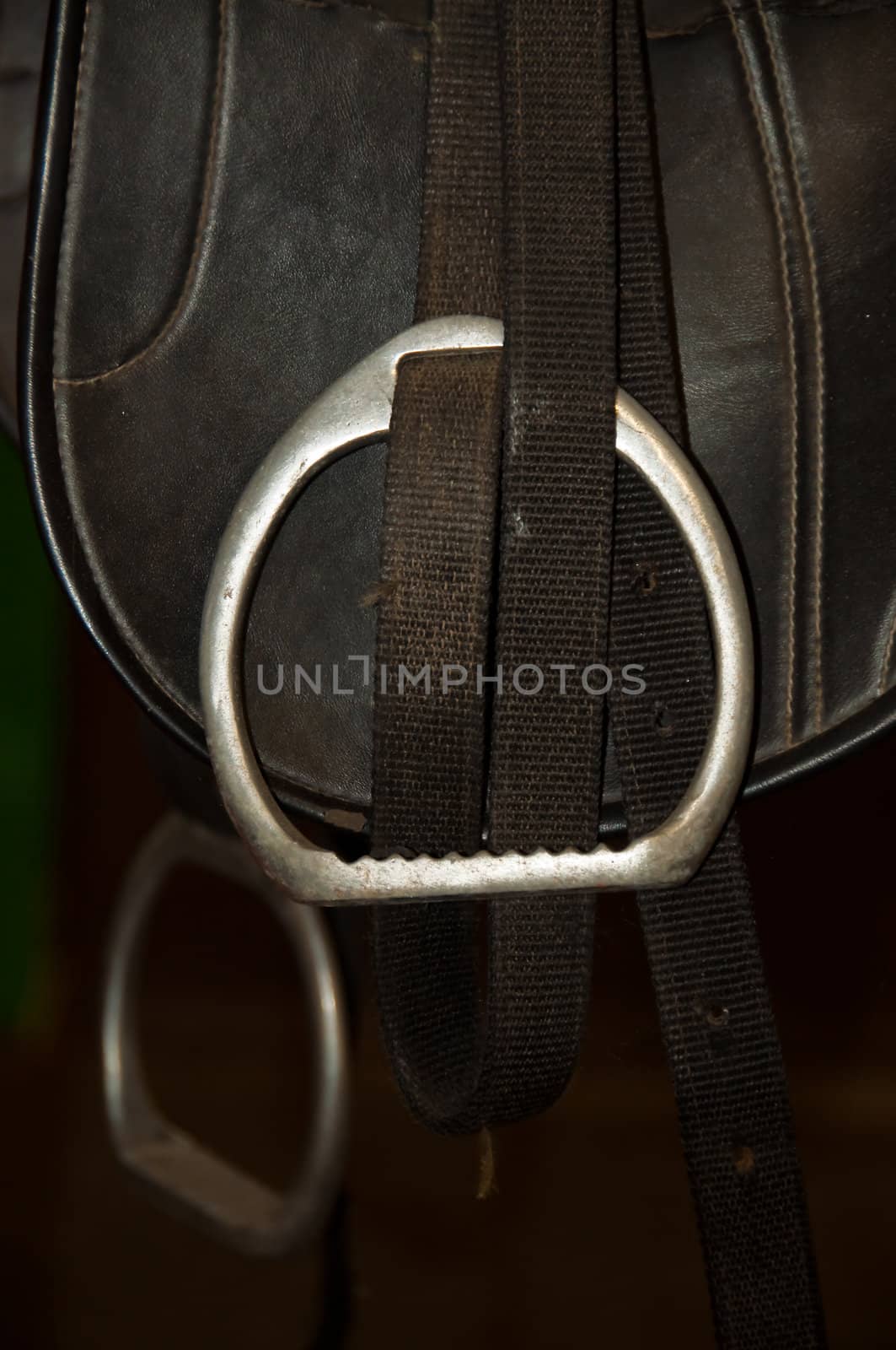 A close-up of a black horse saddle with stirrups